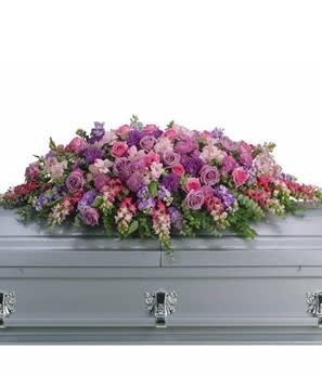 Pink and purple floral casket spray on a gray casket