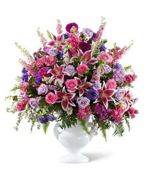 Mixed pink and purple flower arrangement in a white vase