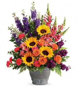 Colorful bouquet with sunflowers, roses, and purple spikes in a gray vase