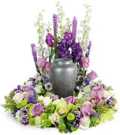 Purple and white floral funeral wreath around a gray urn