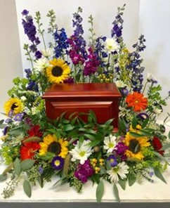 Colorful floral spray surrounding a red casket