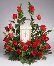 Red roses arranged around a white memorial lantern with a cross