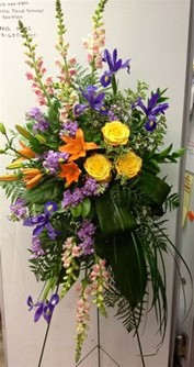 Tall standing floral spray with yellow roses, purple irises, and orange lilies
