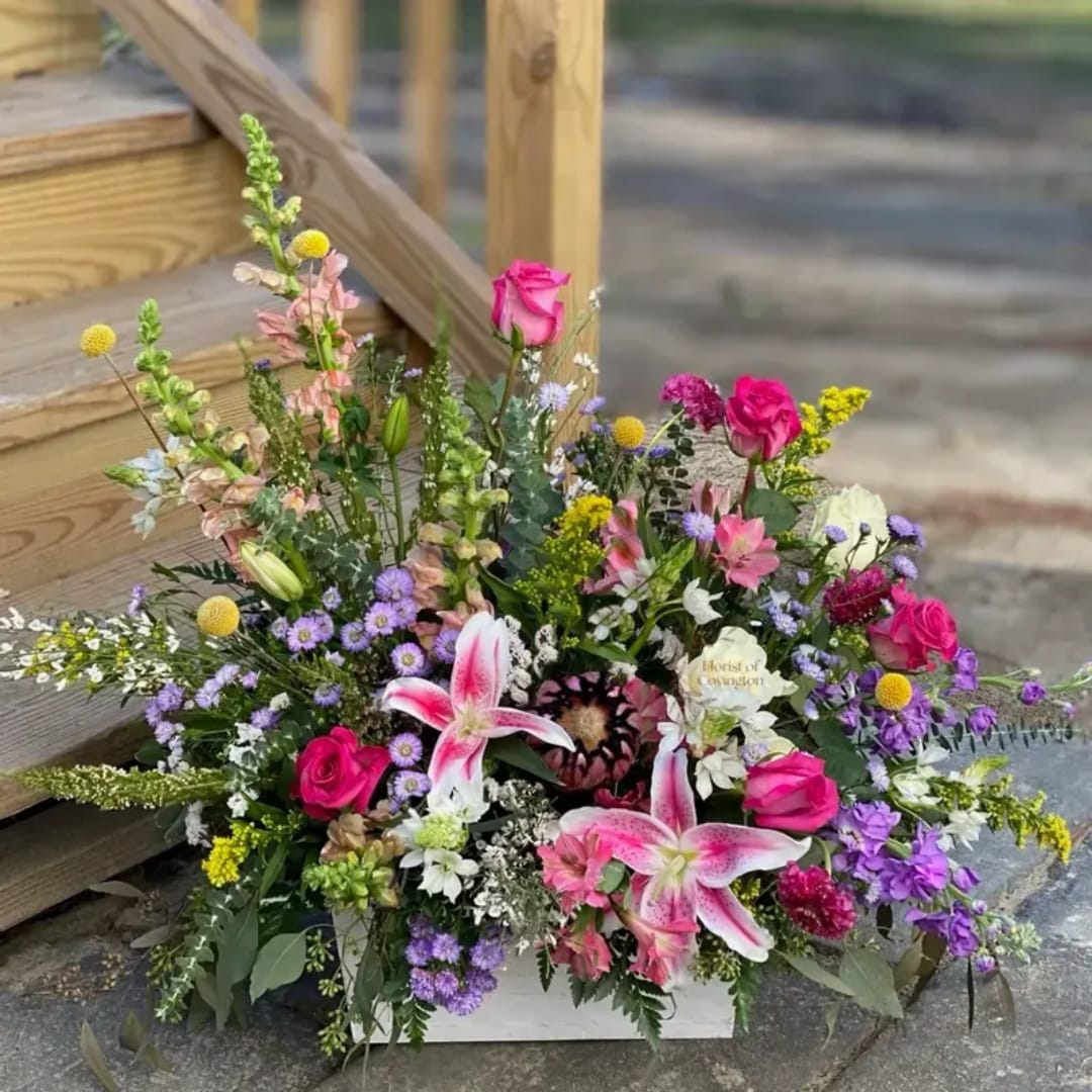 Large mixed flower arrangement in a white box with pink lilies and roses