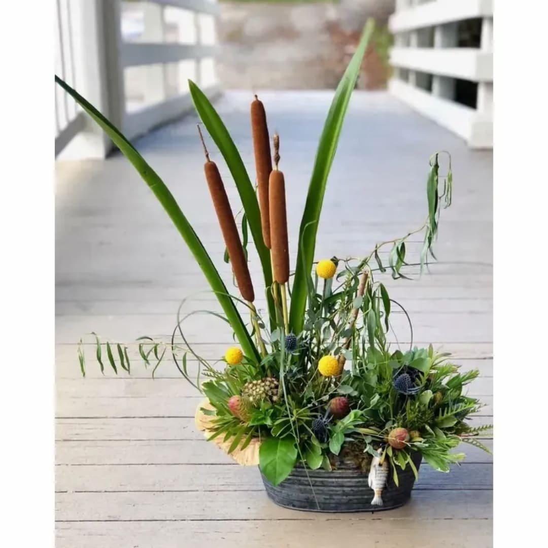 Tall arrangement with cattails and mixed greenery in a low container