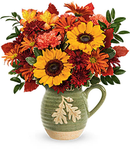 Autumn bouquet of sunflowers and chrysanthemums in a green ceramic pitcher