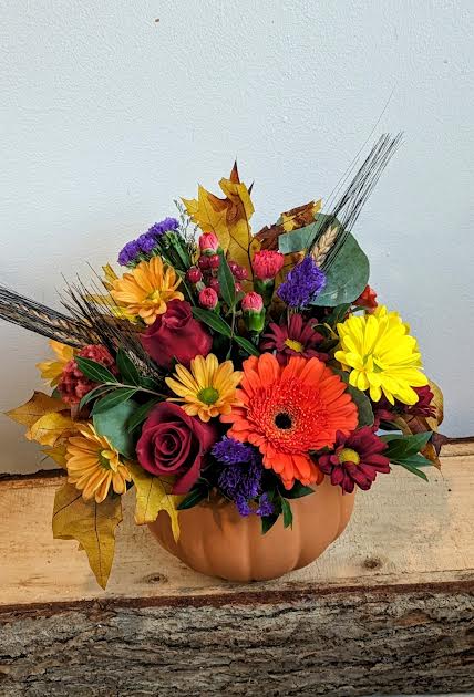 Mixed autumn bouquet in a pumpkin-shaped container with bright flowers