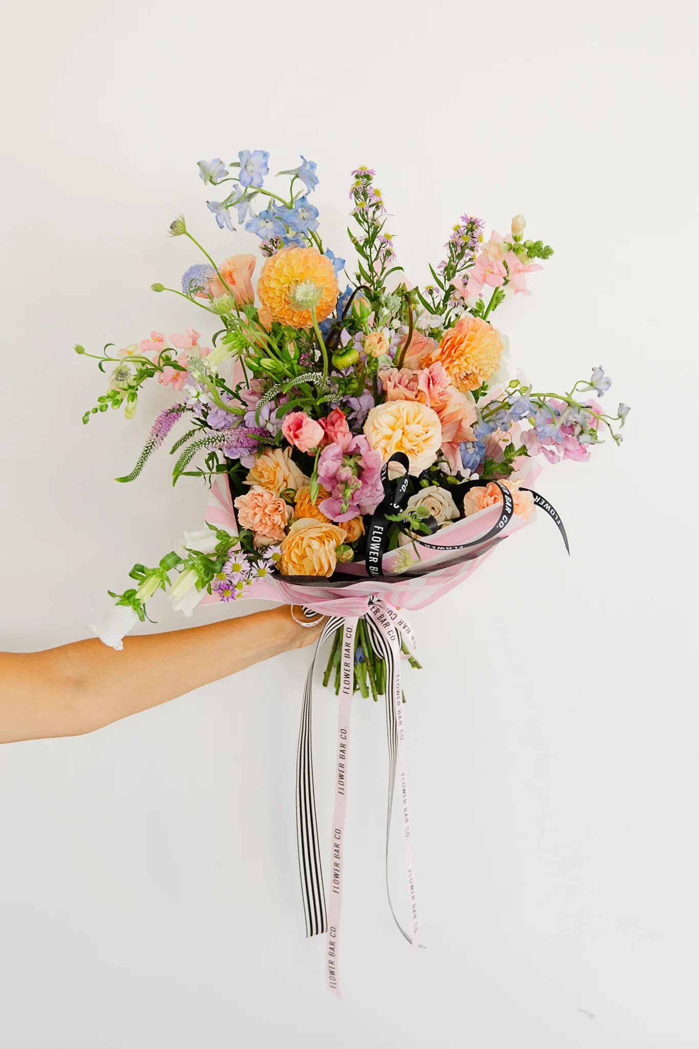 Designer's Choice Spring Wrapped No Vase Flower Bouquet $100 Value  - Let our designer create a one-of-a-kind wrapped bouquet using the freshest flowers of the season. Each Designer’s Choice arrangement is thoughtfully crafted based on daily availability and the value selected. Flower types and colors will vary, and no specific flowers or design can be guaranteed.