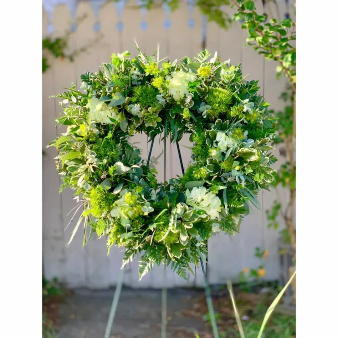 Heart-shaped green floral wreath on a stand outdoors