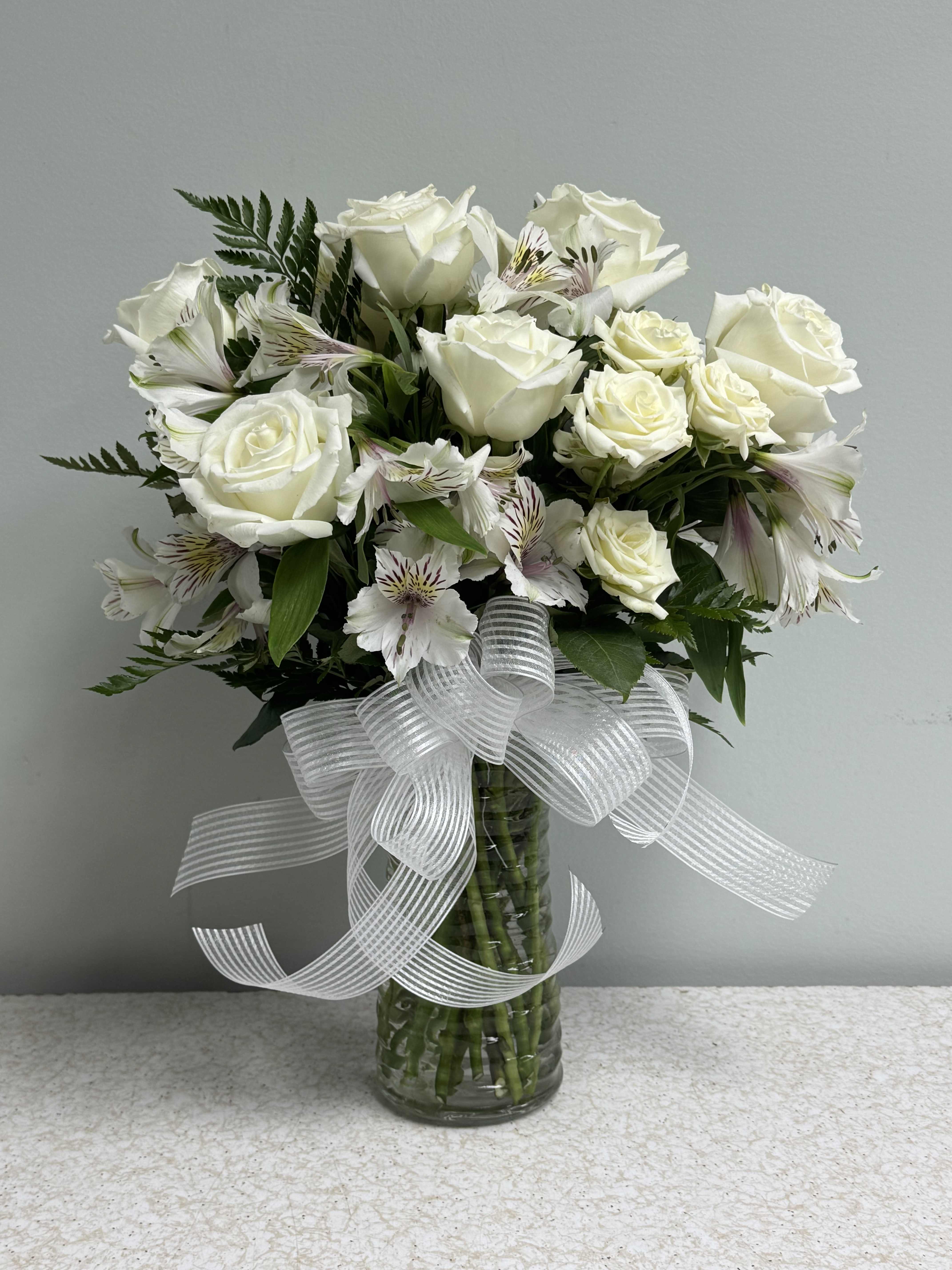 White rose bouquet in a glass vase with a sheer ribbon bow