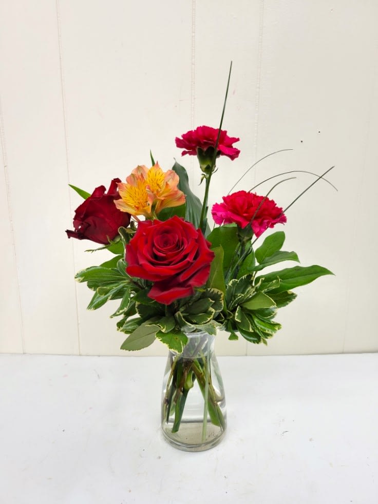 Mixed bouquet of red roses and pink carnations in a clear glass vase