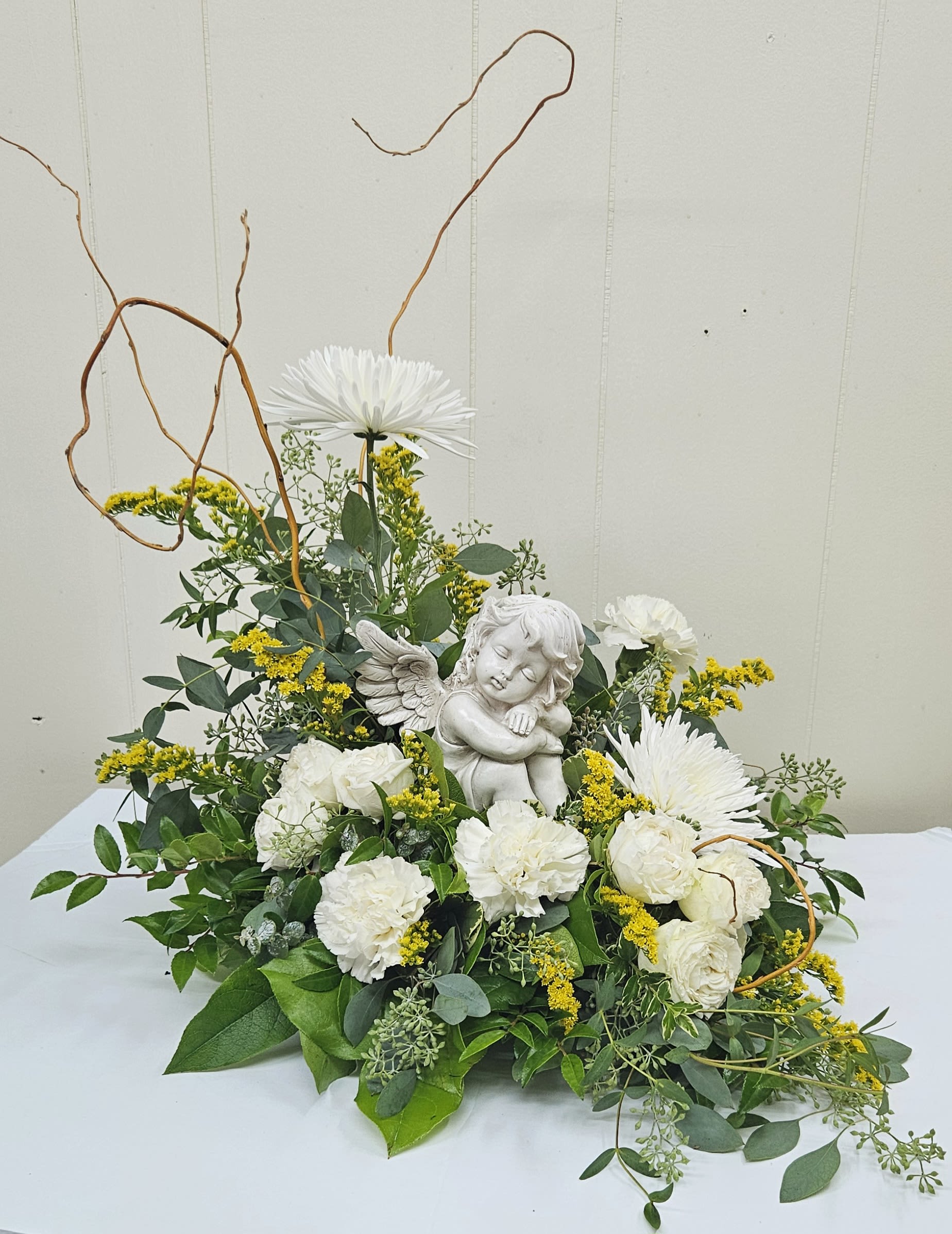 White flowers arranged around a small angel figurine with curly branches