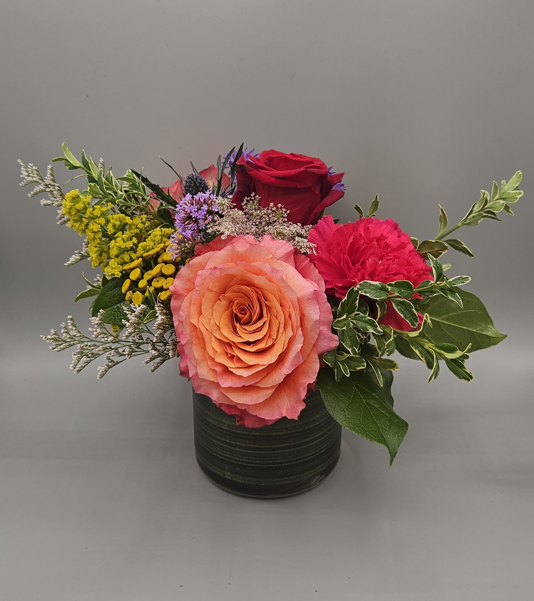 Mixed flower arrangement in a black vase with roses and carnations