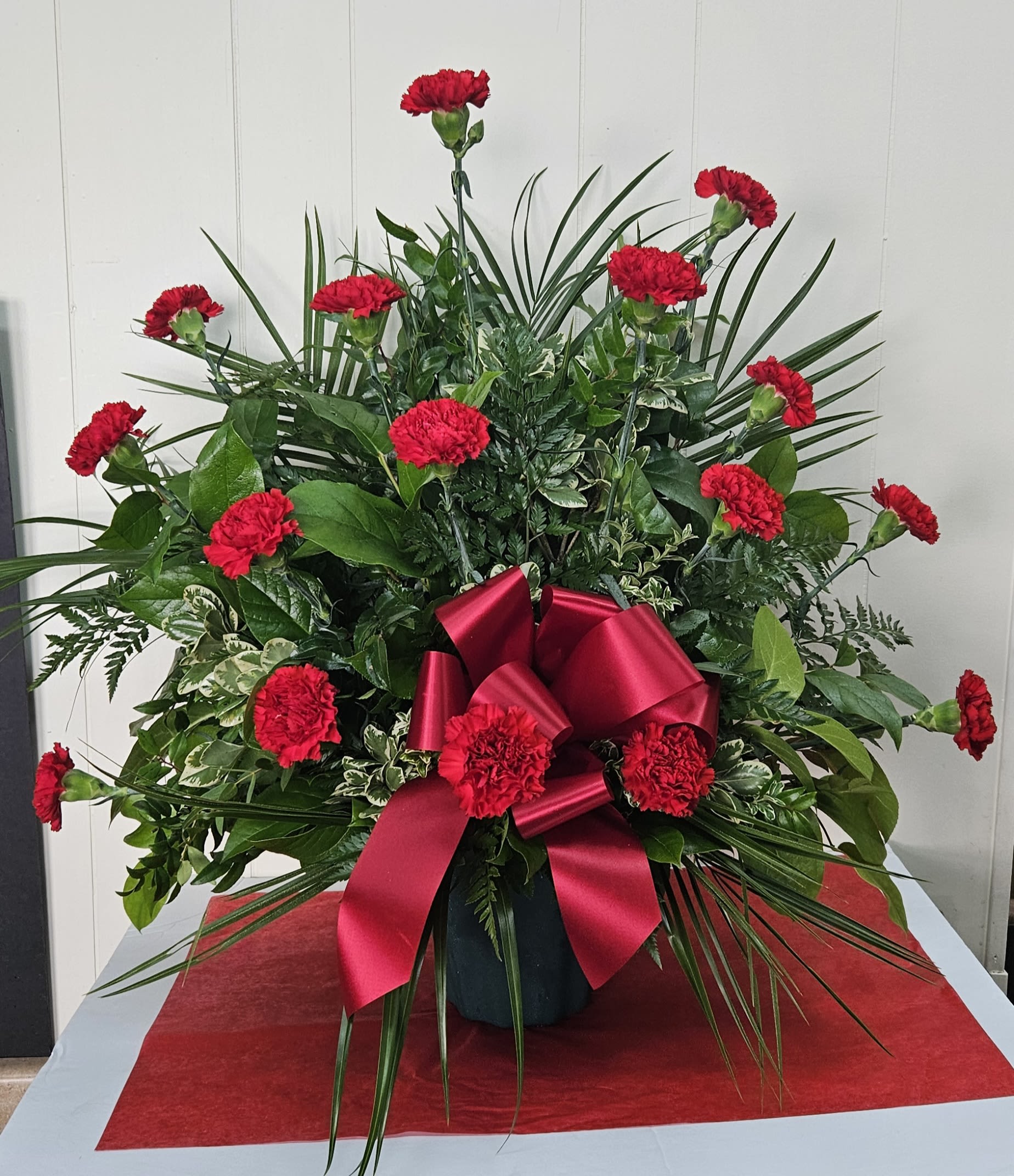 Red carnations in a vase with a large red ribbon