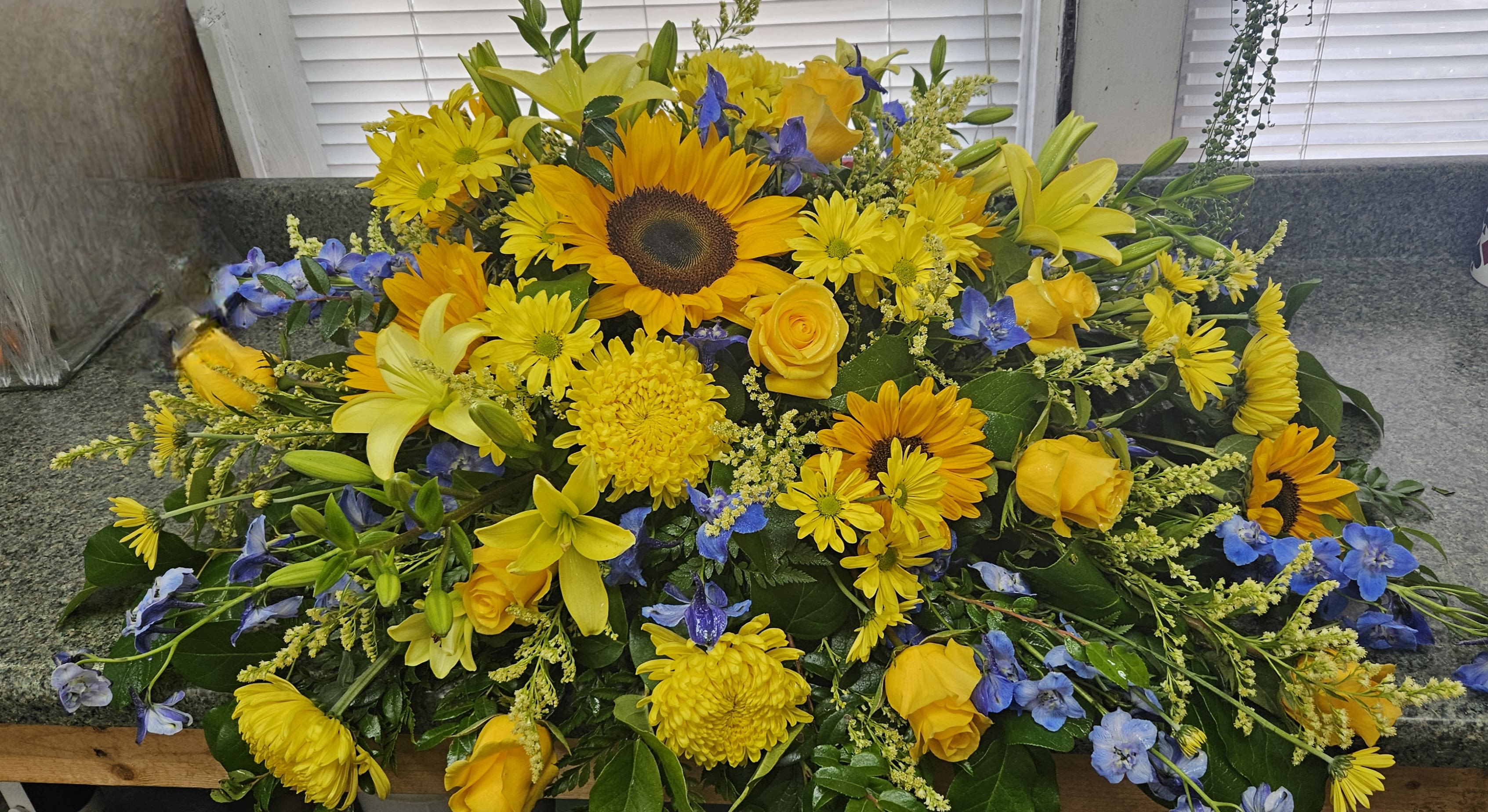 Yellow and blue mixed flower arrangement with sunflowers and roses