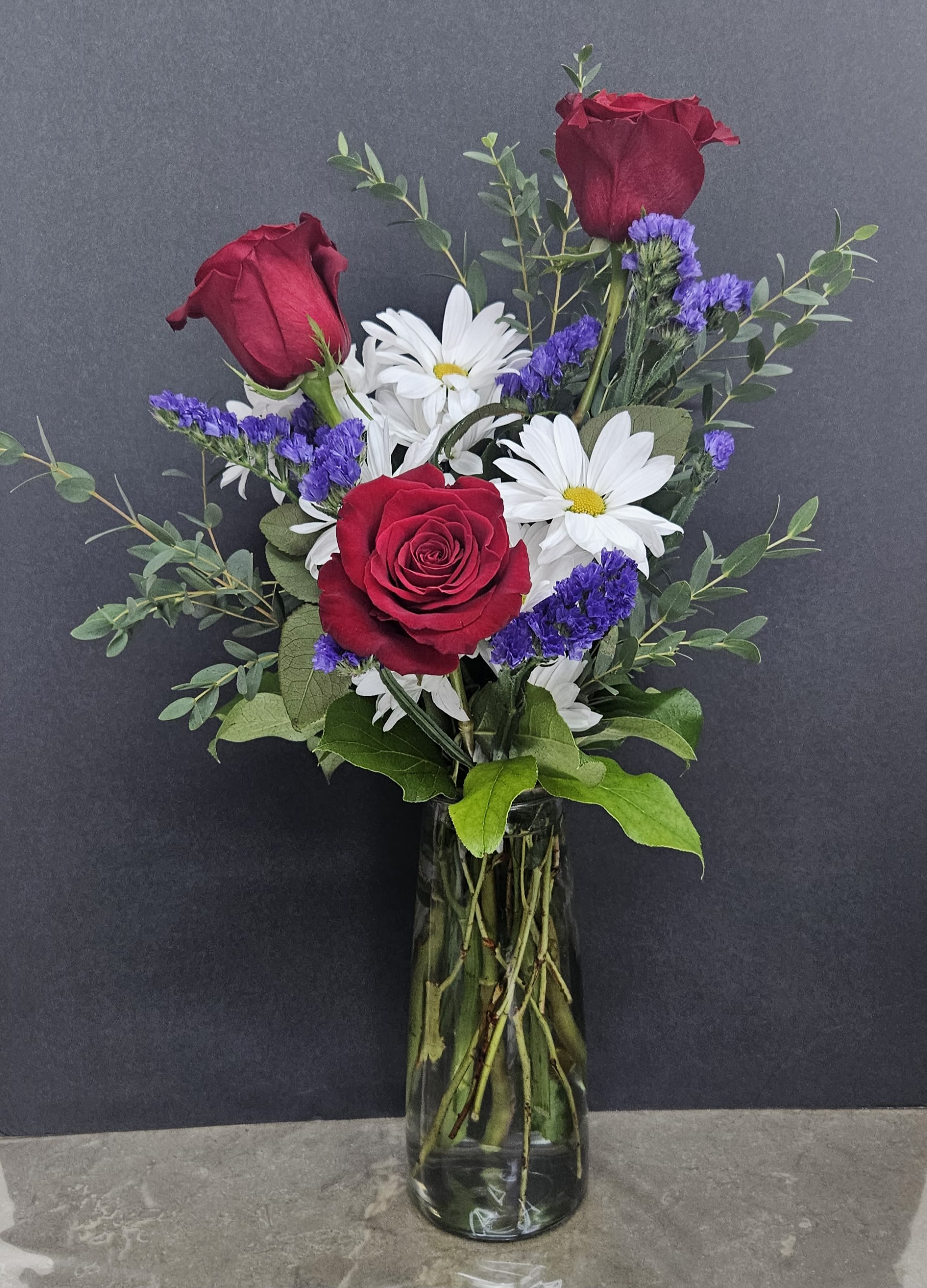 Red roses and white daisies in a glass vase