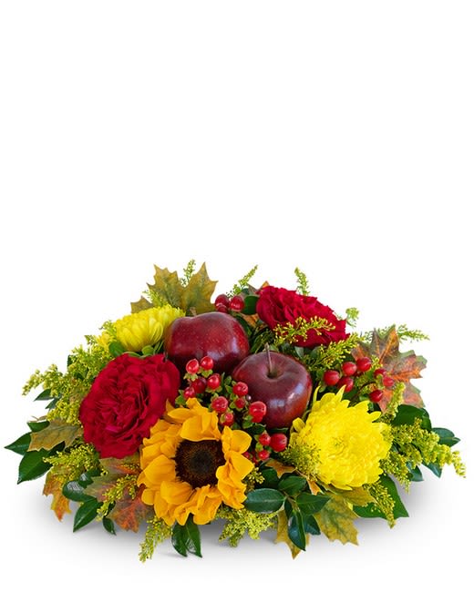 Autumn floral arrangement with red roses, yellow flowers, and decorative apples