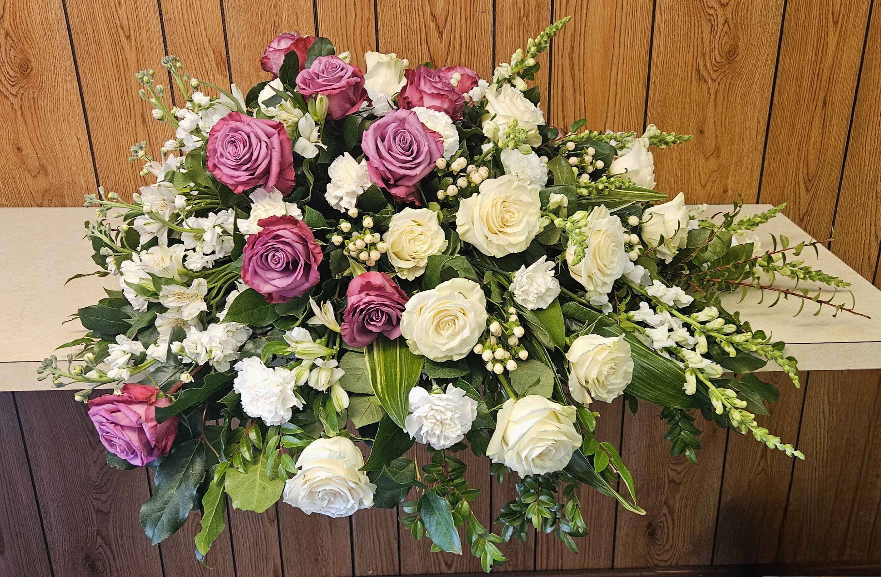 Casket spray with pink and white roses and mixed white flowers