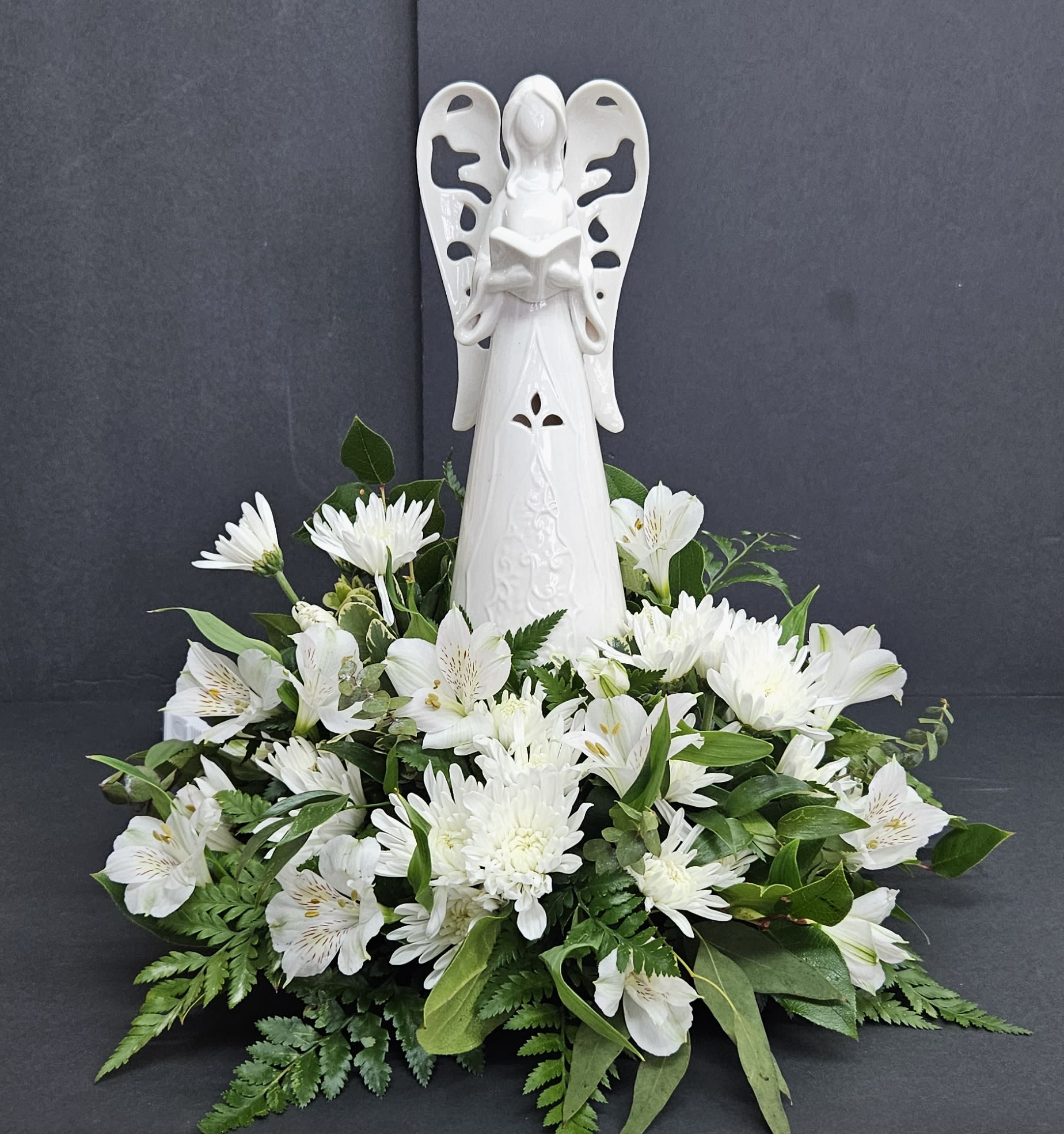 White angel figurine above a low arrangement of white flowers