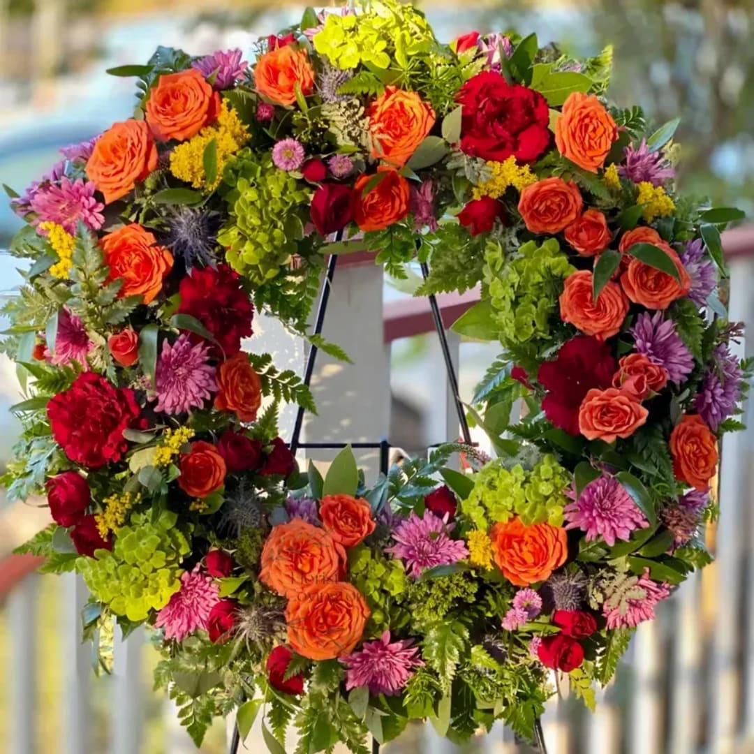 Colorful floral wreath with roses and mixed blooms on a stand