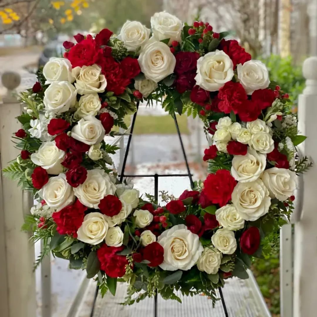 Circular wreath of red and white roses on a black stand
