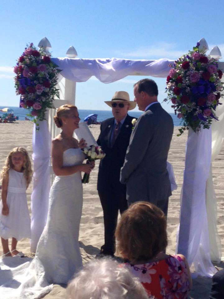 Beach wedding arch decorated with pink and purple flowers