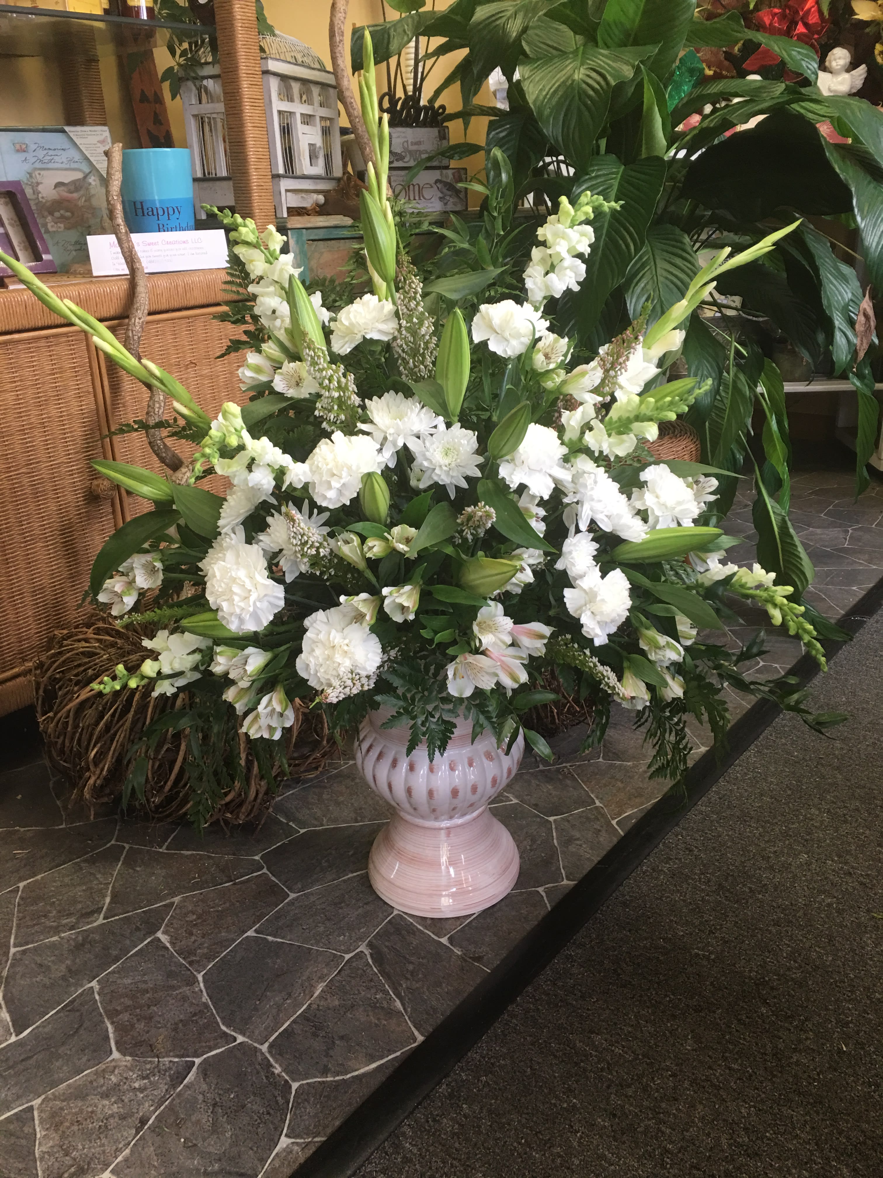 Large white floral arrangement in a pink pedestal vase