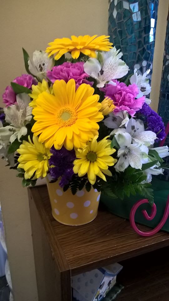 Bouquet of yellow daisies, purple carnations, and white alstroemeria in a polka-dot vase