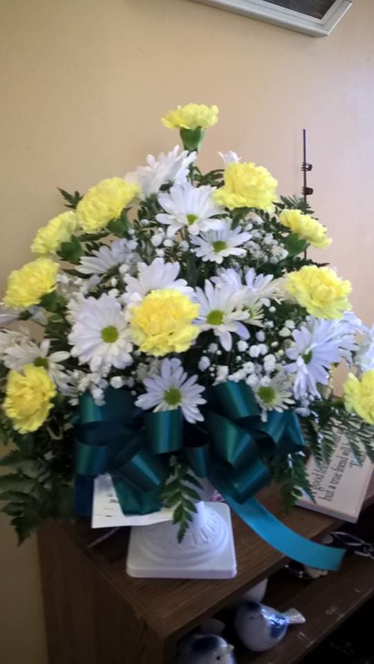 White daisies and yellow carnations in a teal ribboned arrangement