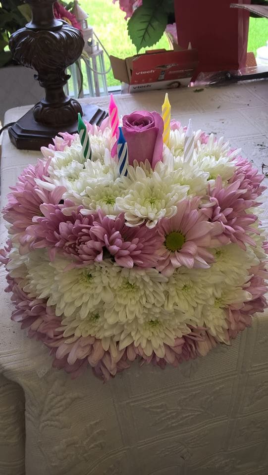Round bouquet of pink and white daisies with a purple rose and birthday candles
