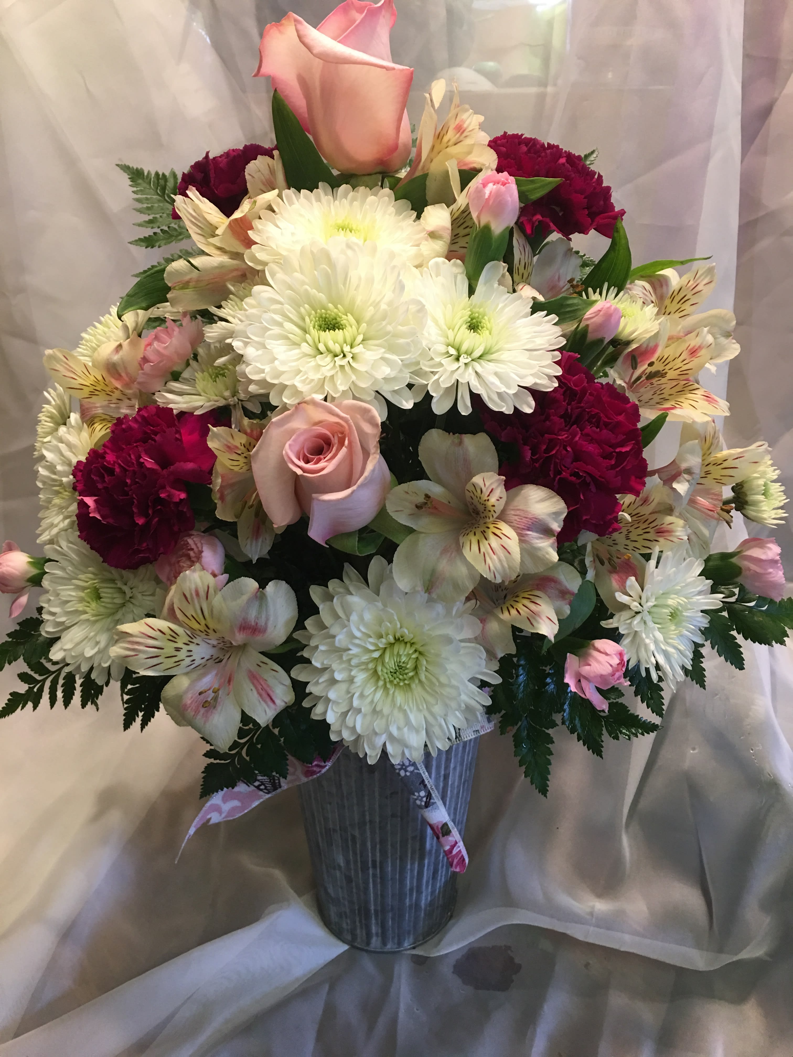 Mixed bouquet in a ribbed vase with pink roses, white mums, and burgundy carnations