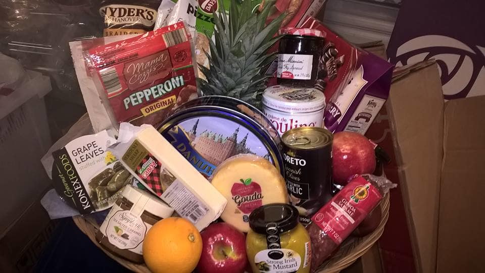 Gift basket with assorted snacks, cheese, fruit, and a pineapple centerpiece