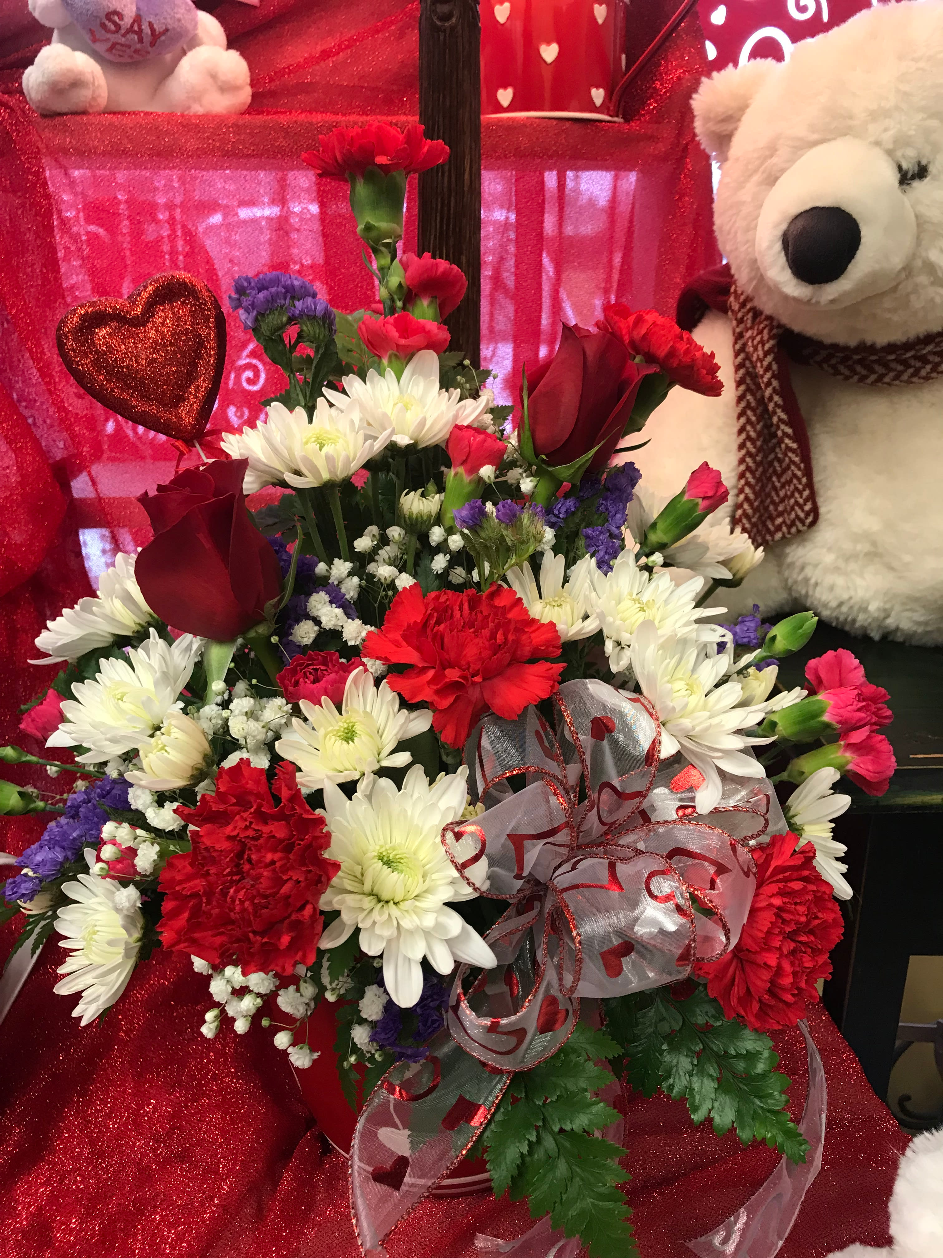 Red and white flower arrangement with a teddy bear and heart decorations
