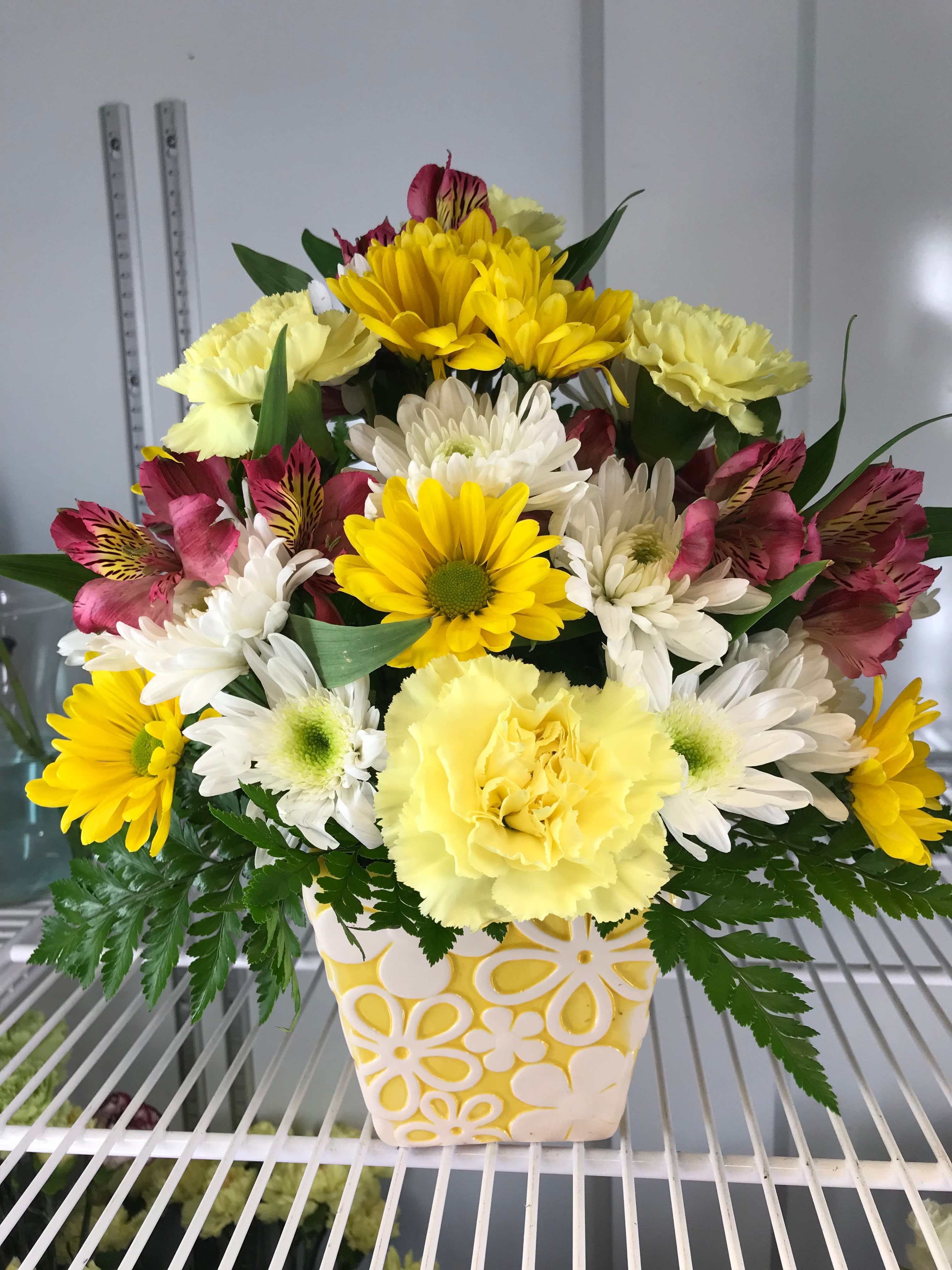 Yellow and white mixed flower arrangement in a patterned ceramic vase