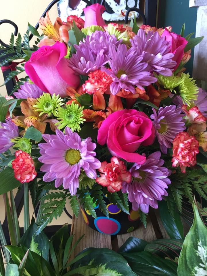 Bouquet of pink roses, purple daisies, and mixed blooms in a decorated vase