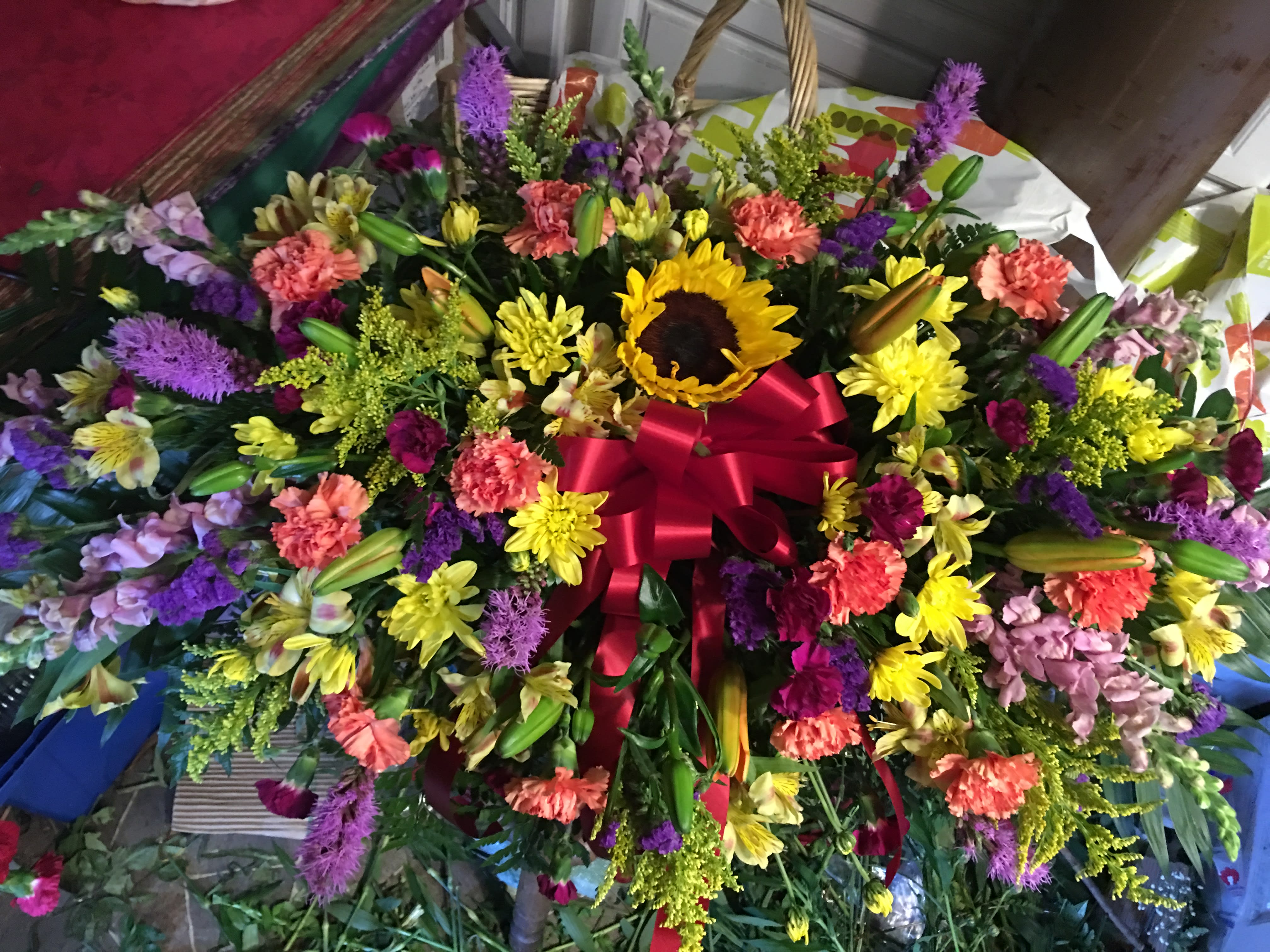 Large mixed flower spray with a red ribbon and sunflower center