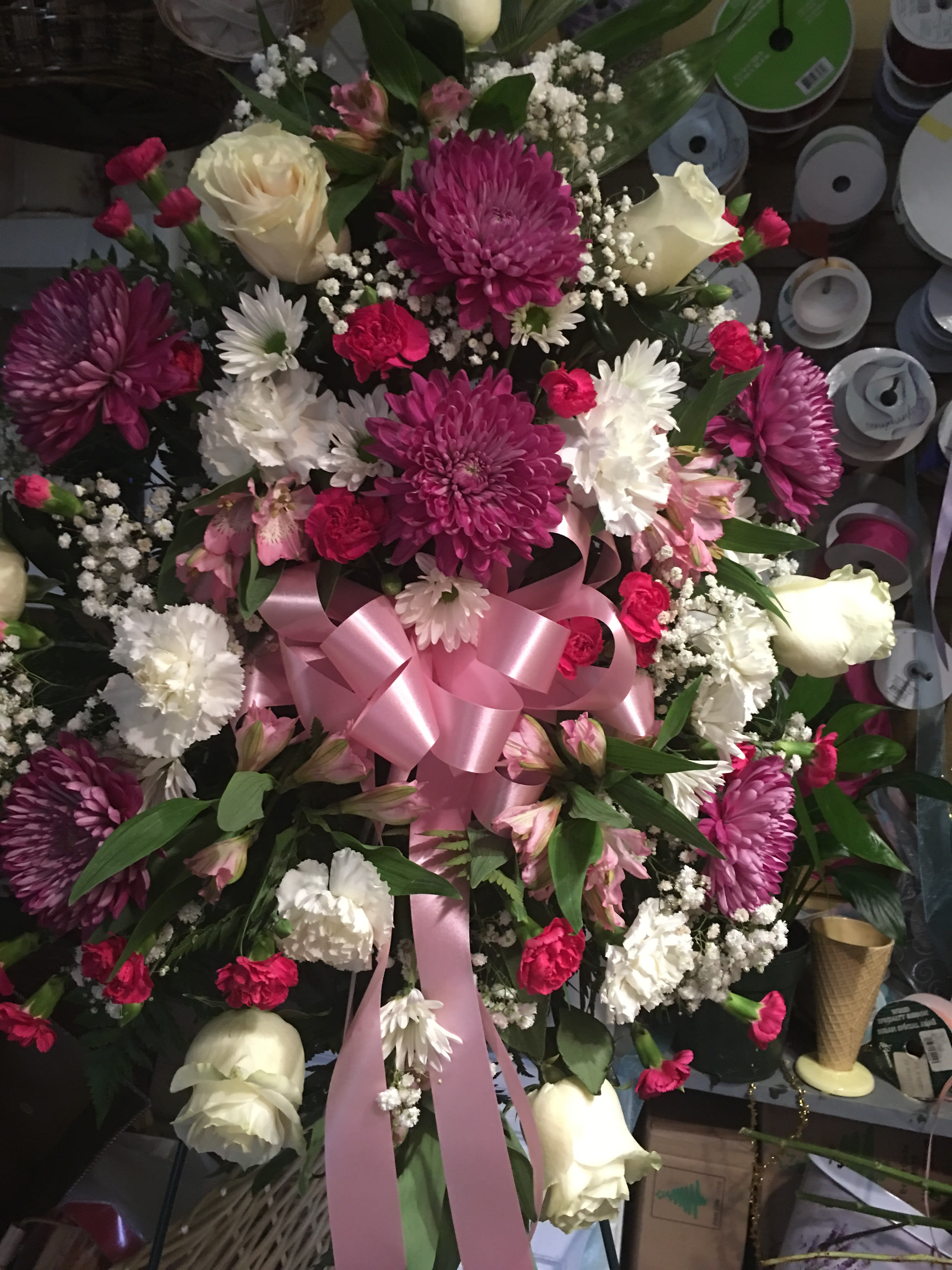 Large bouquet of pink, white, and cream flowers with a pink ribbon