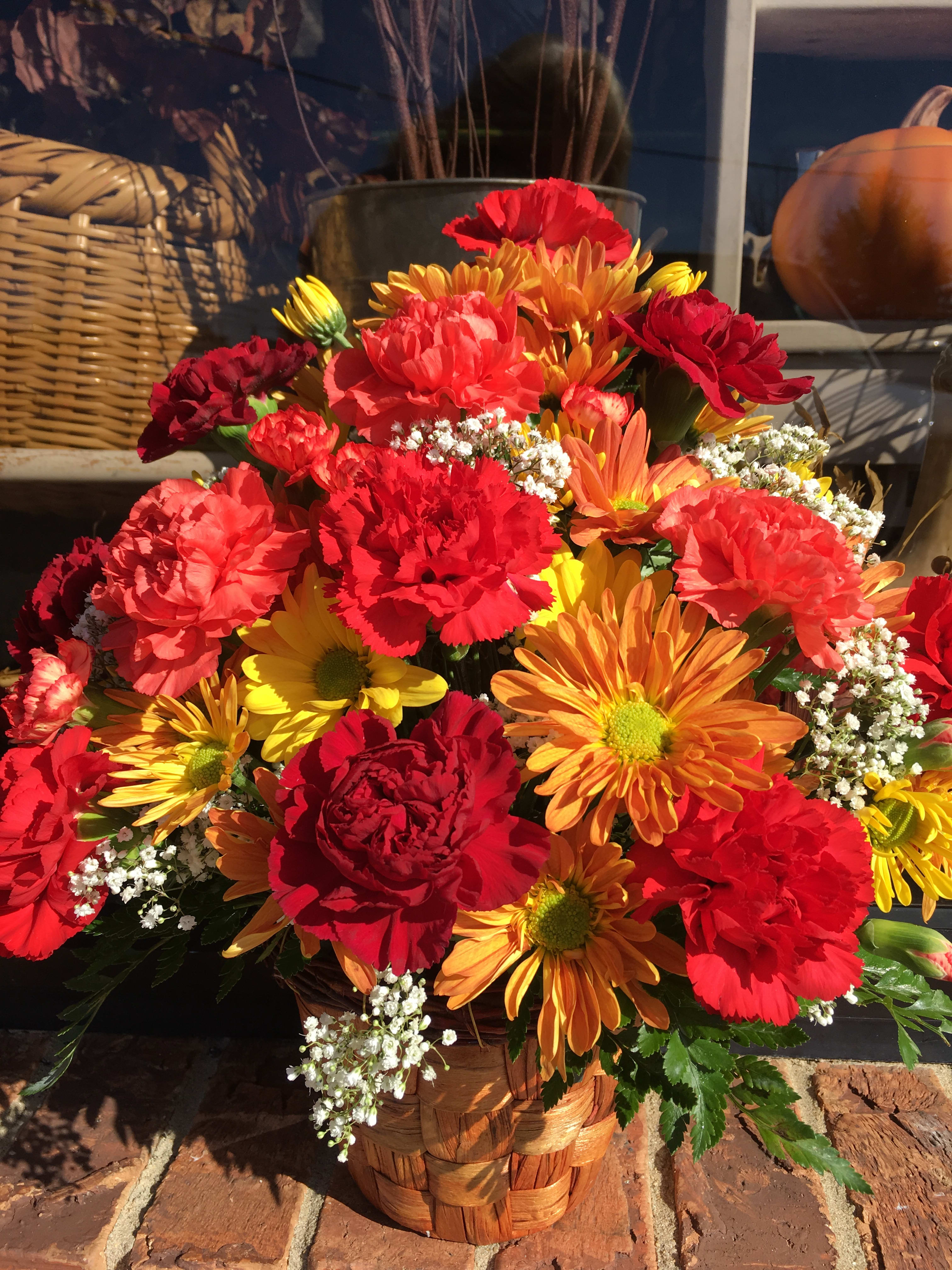 Basket arrangement of red, orange, and yellow flowers