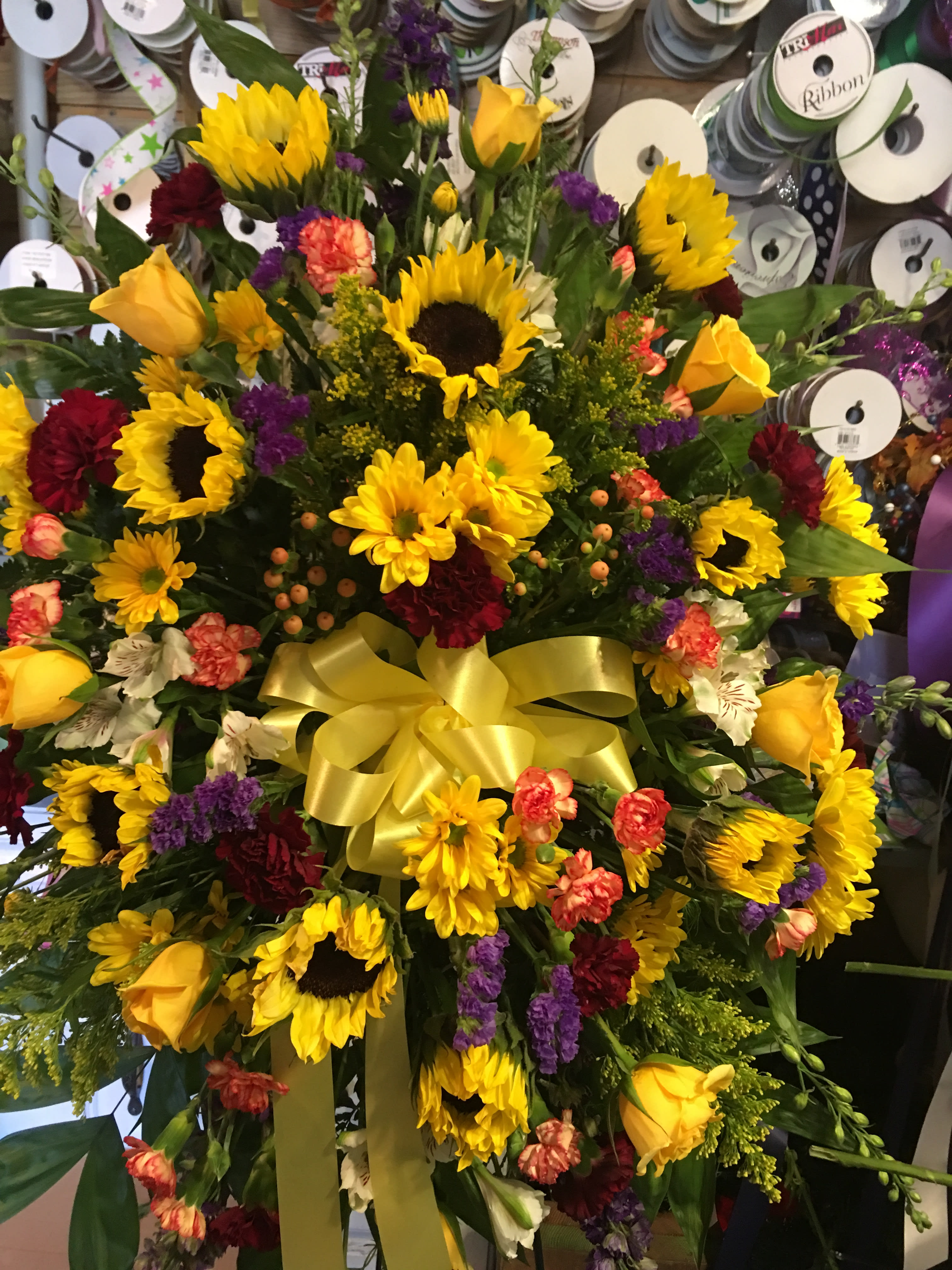 Large bouquet with sunflowers, yellow roses, and mixed flowers tied with a yellow ribbon