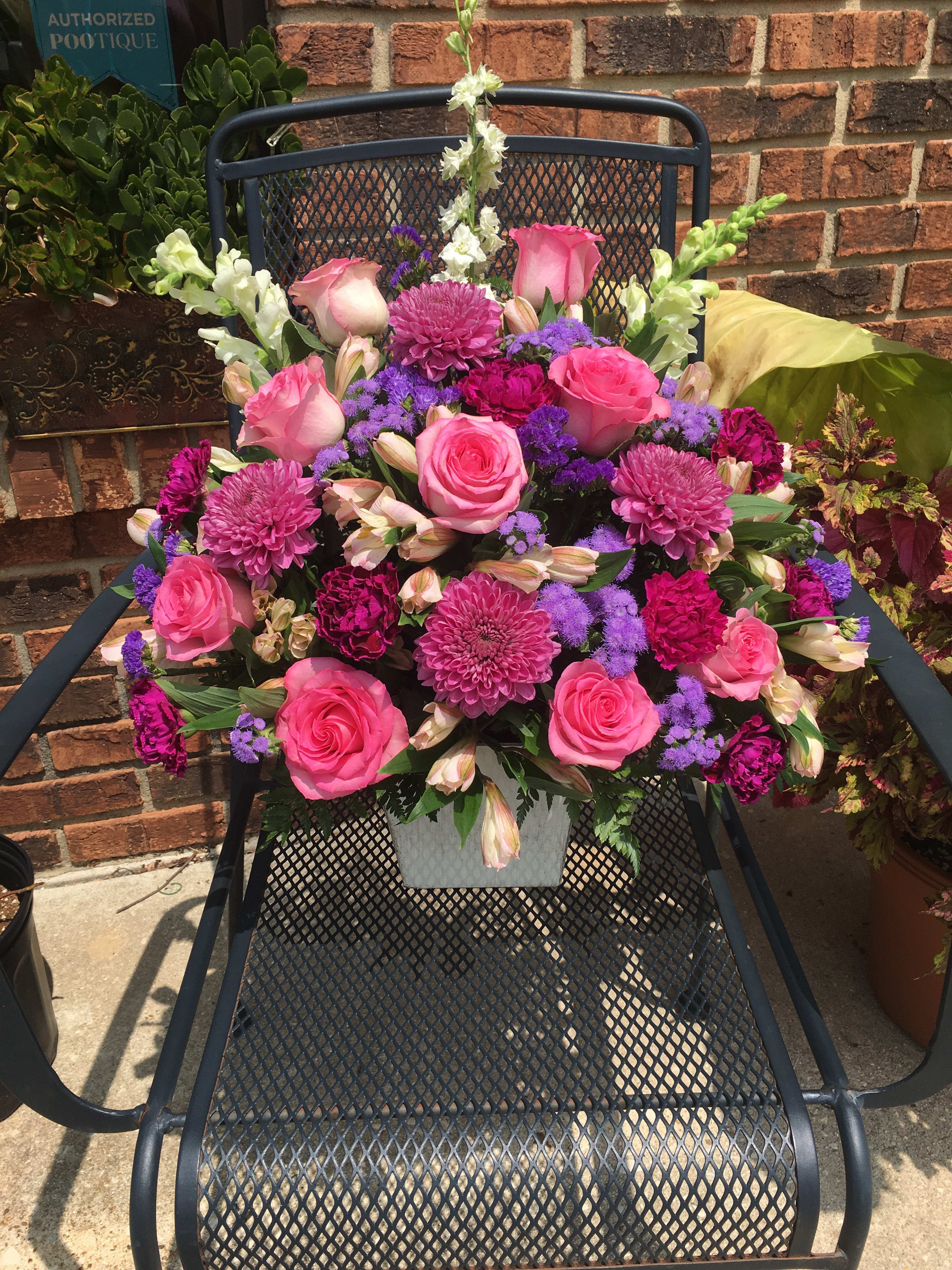Pink and purple mixed flower arrangement in a white container