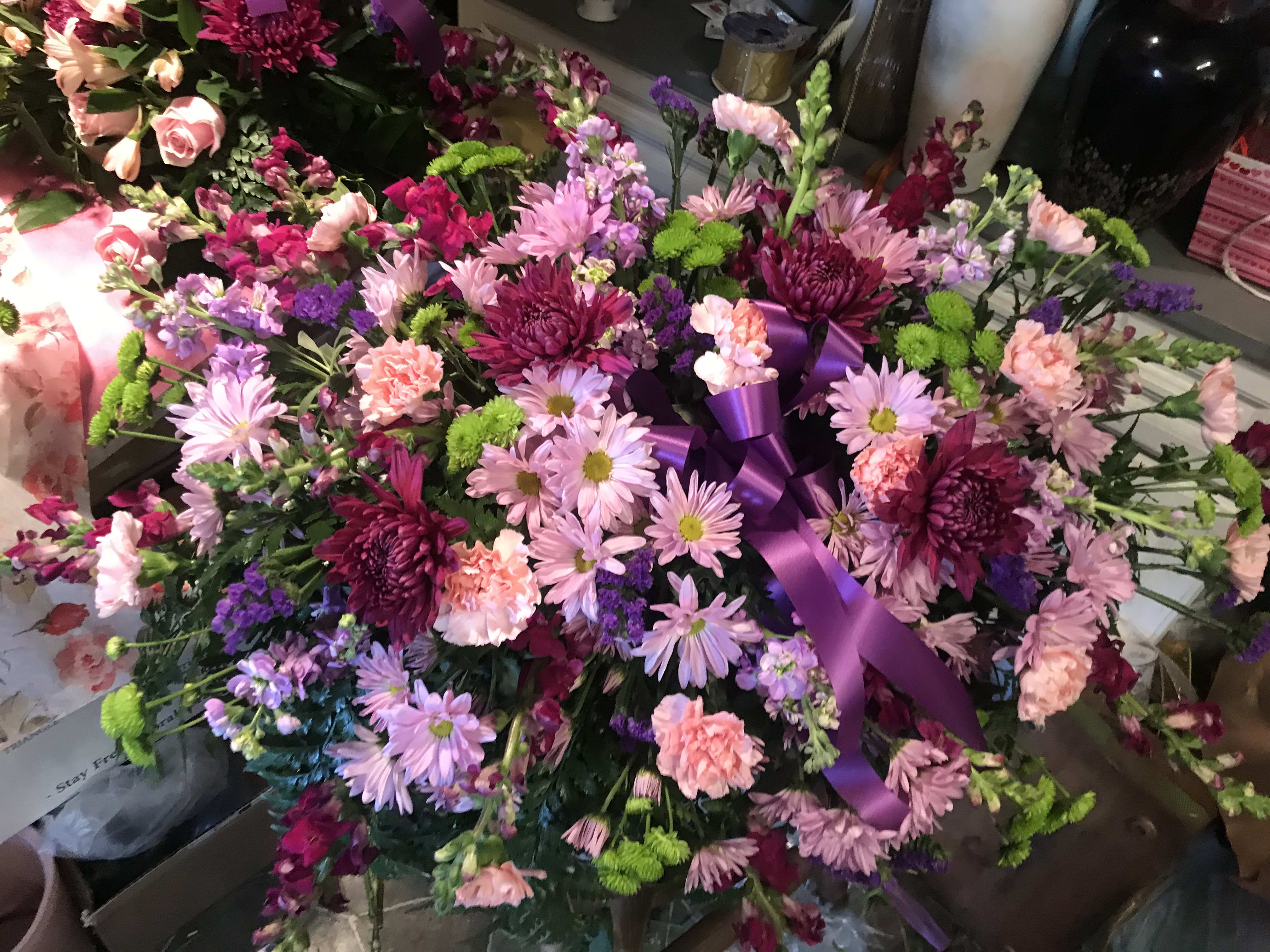Large pink and purple floral arrangement with a purple ribbon