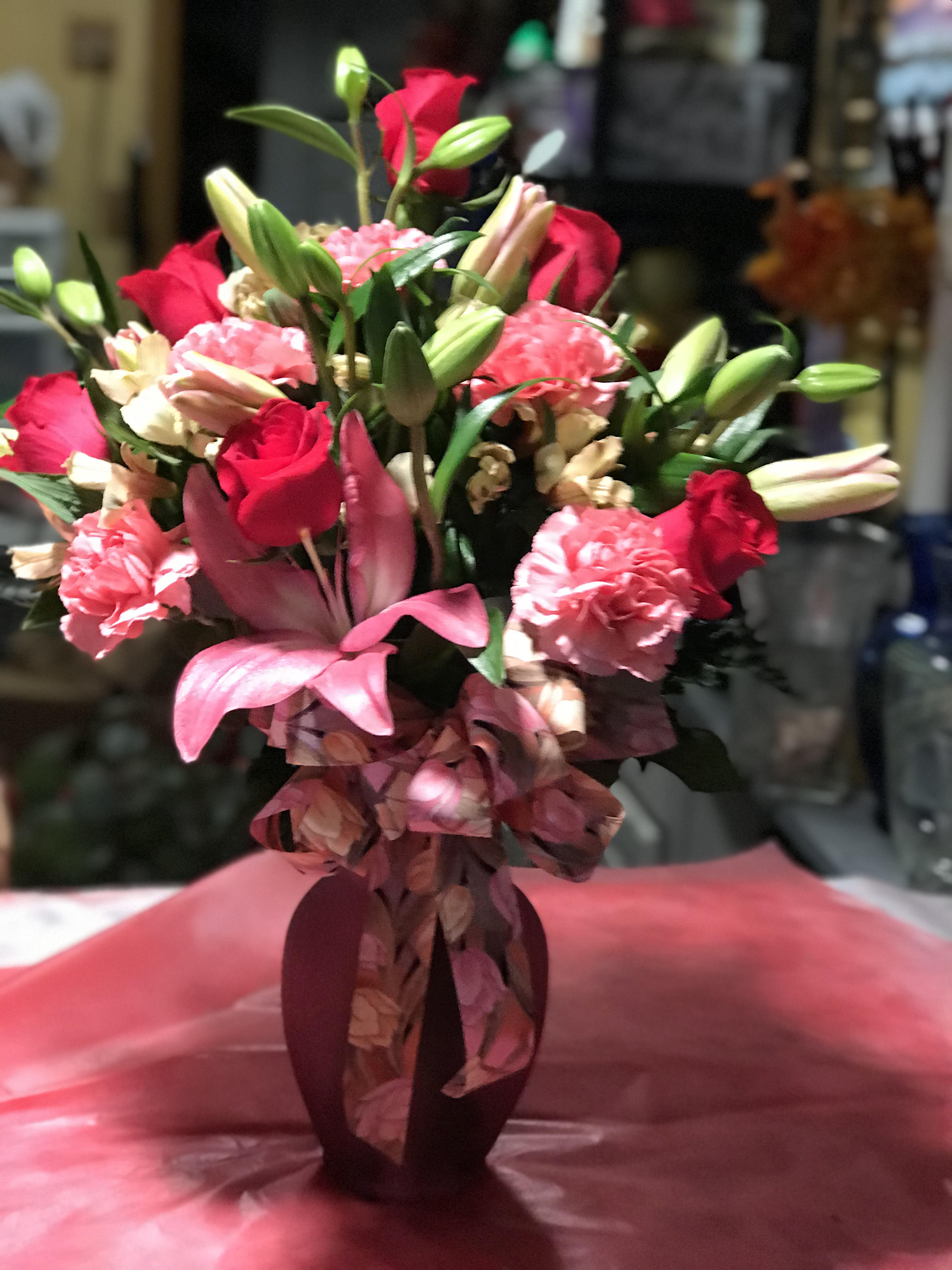 Bouquet of red roses, pink lilies, and carnations in a vase