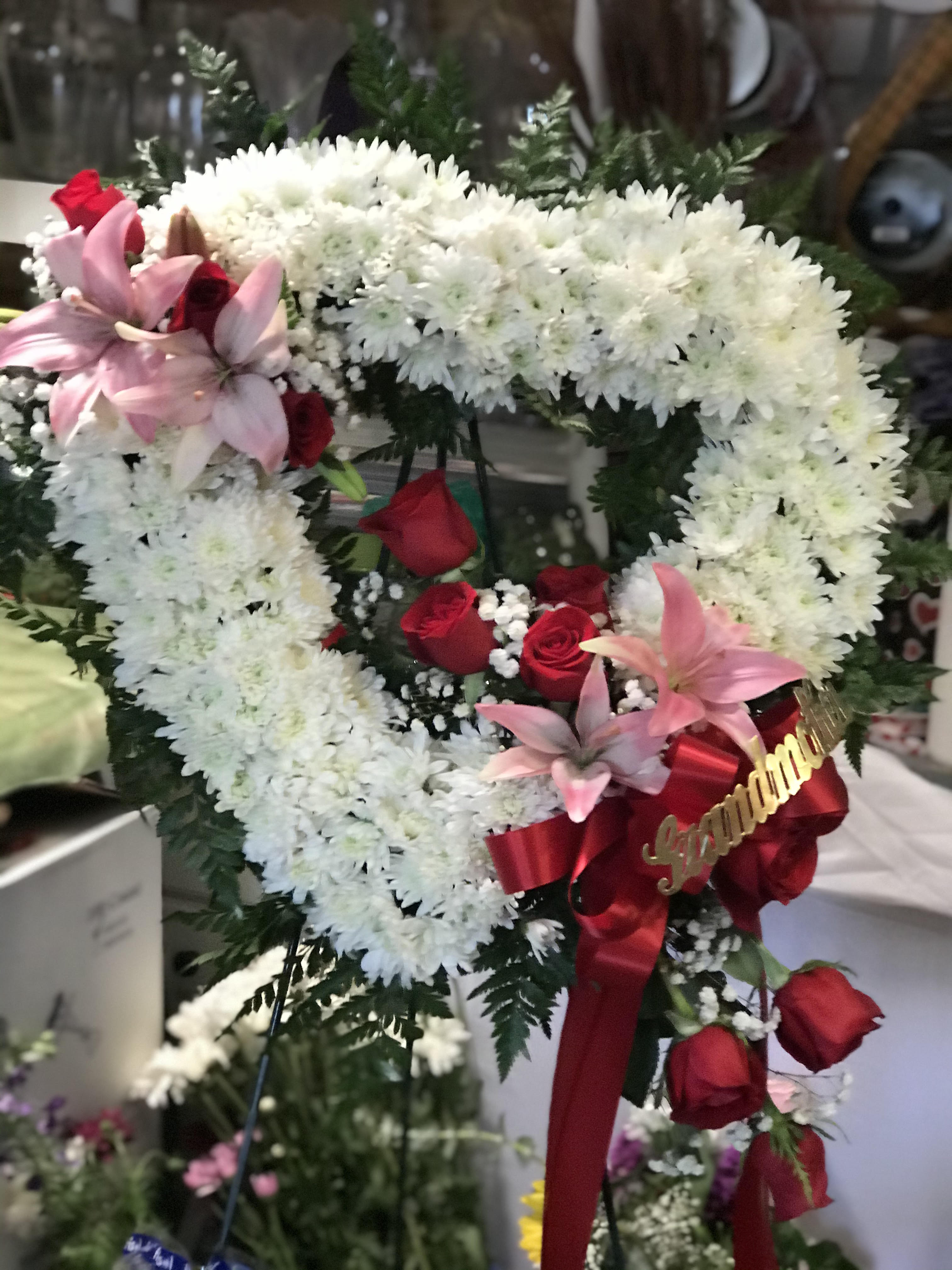 Heart-shaped floral wreath with white chrysanthemums, red roses, and pink lilies