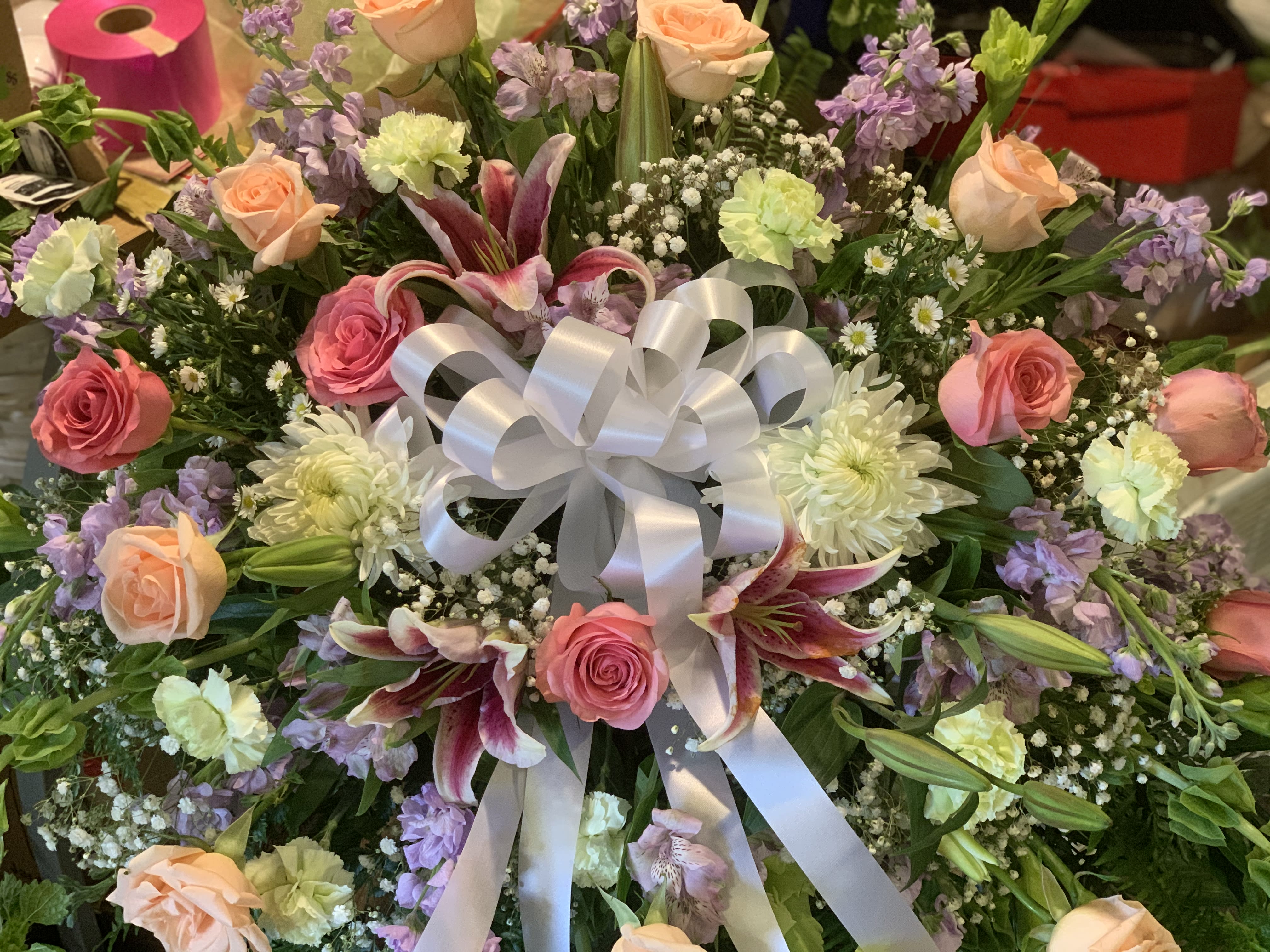 Mixed bouquet with roses, lilies, and a white ribbon bow