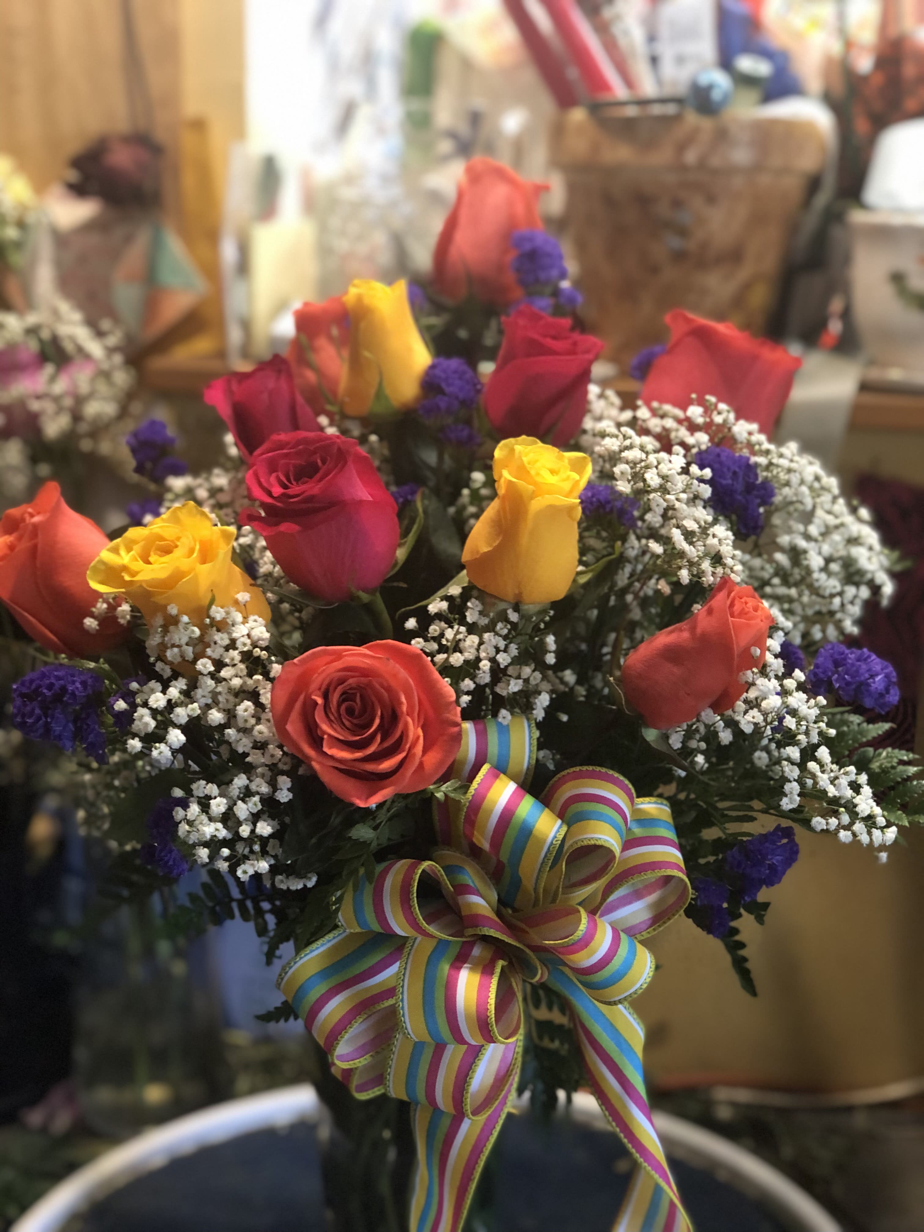 Bouquet of multicolored roses with baby's breath and a striped ribbon bow