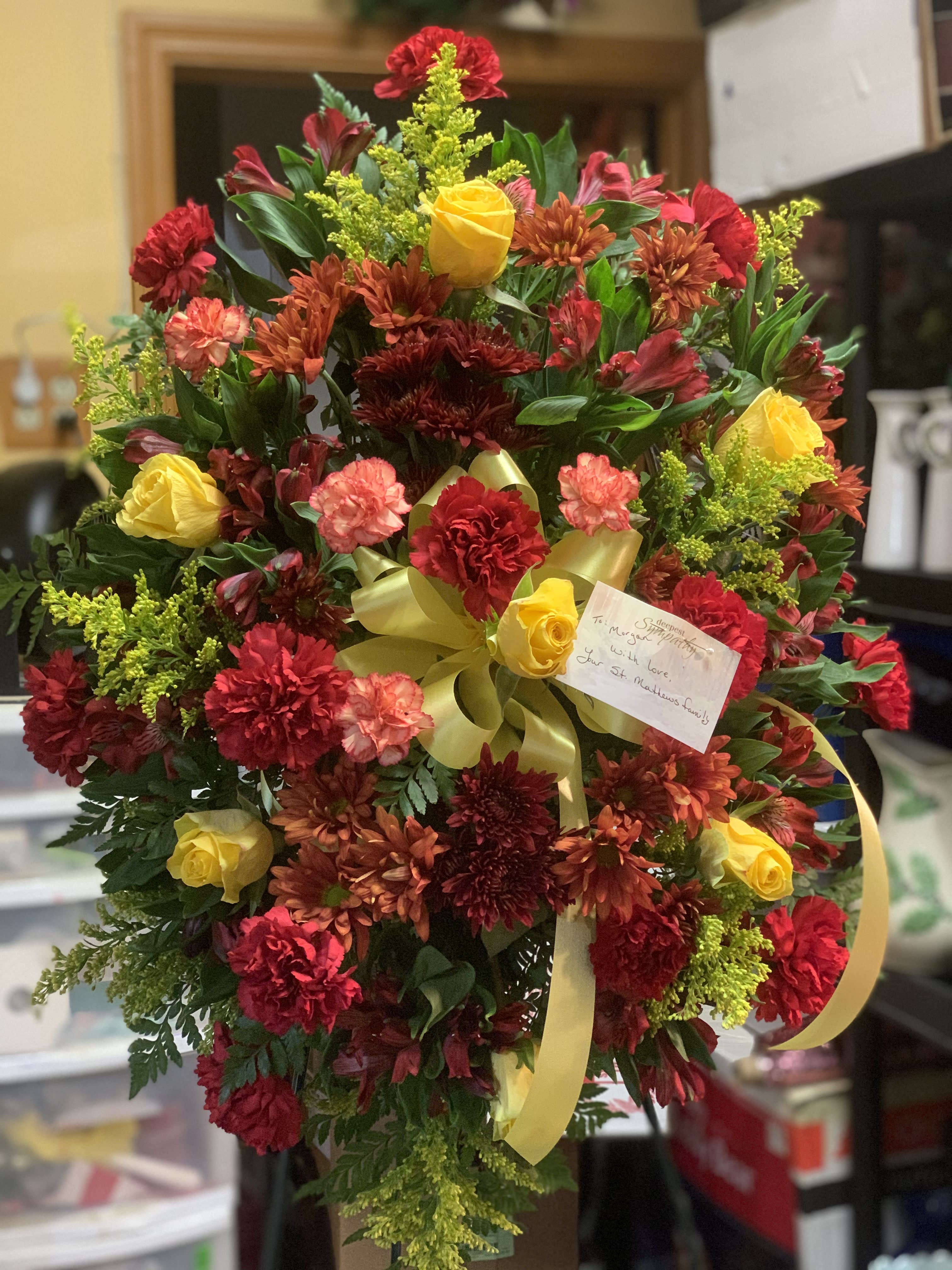 Large bouquet of red, yellow, and orange flowers with a yellow ribbon