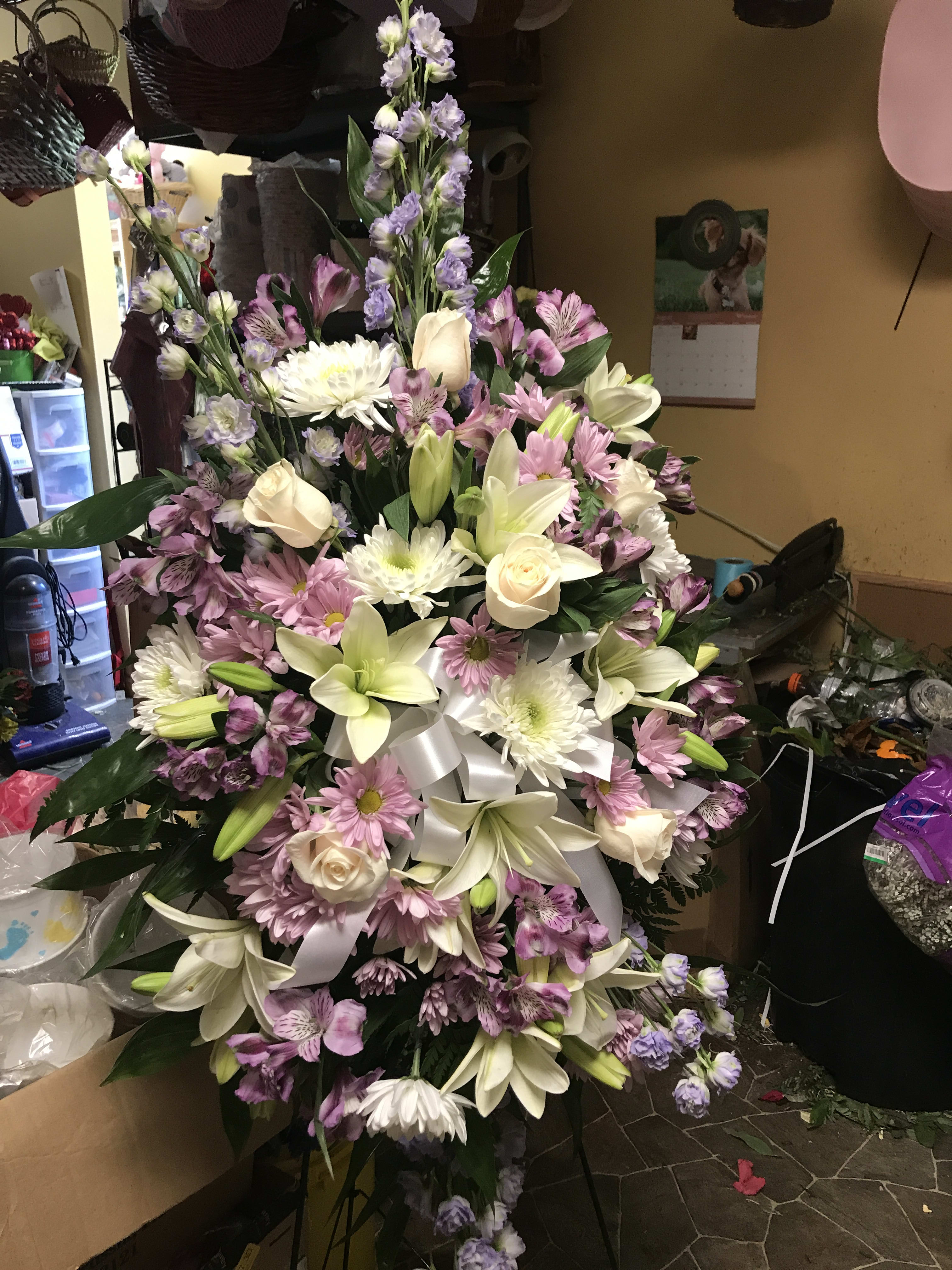 Large pastel floral spray with lilies, roses, daisies, and purple filler flowers