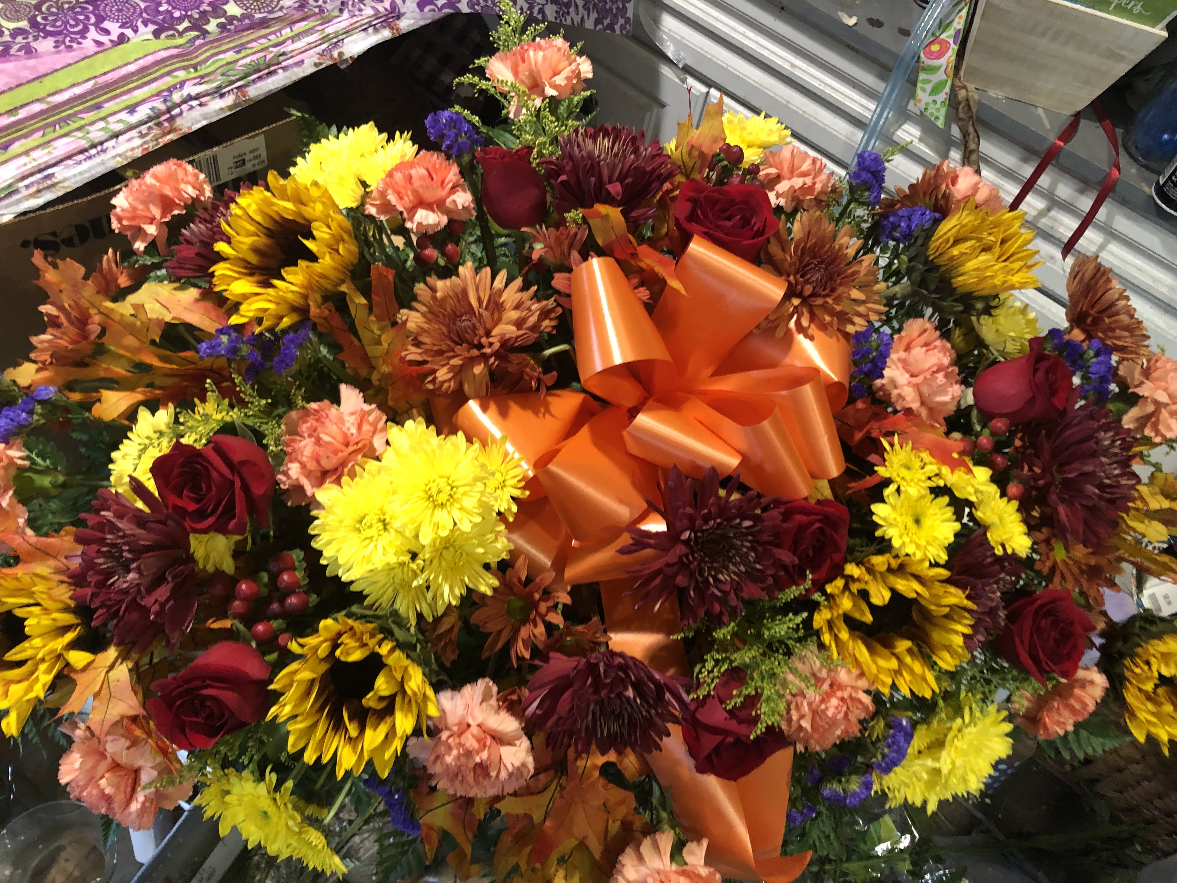 Large mixed bouquet with roses, chrysanthemums, and carnations in orange wrap