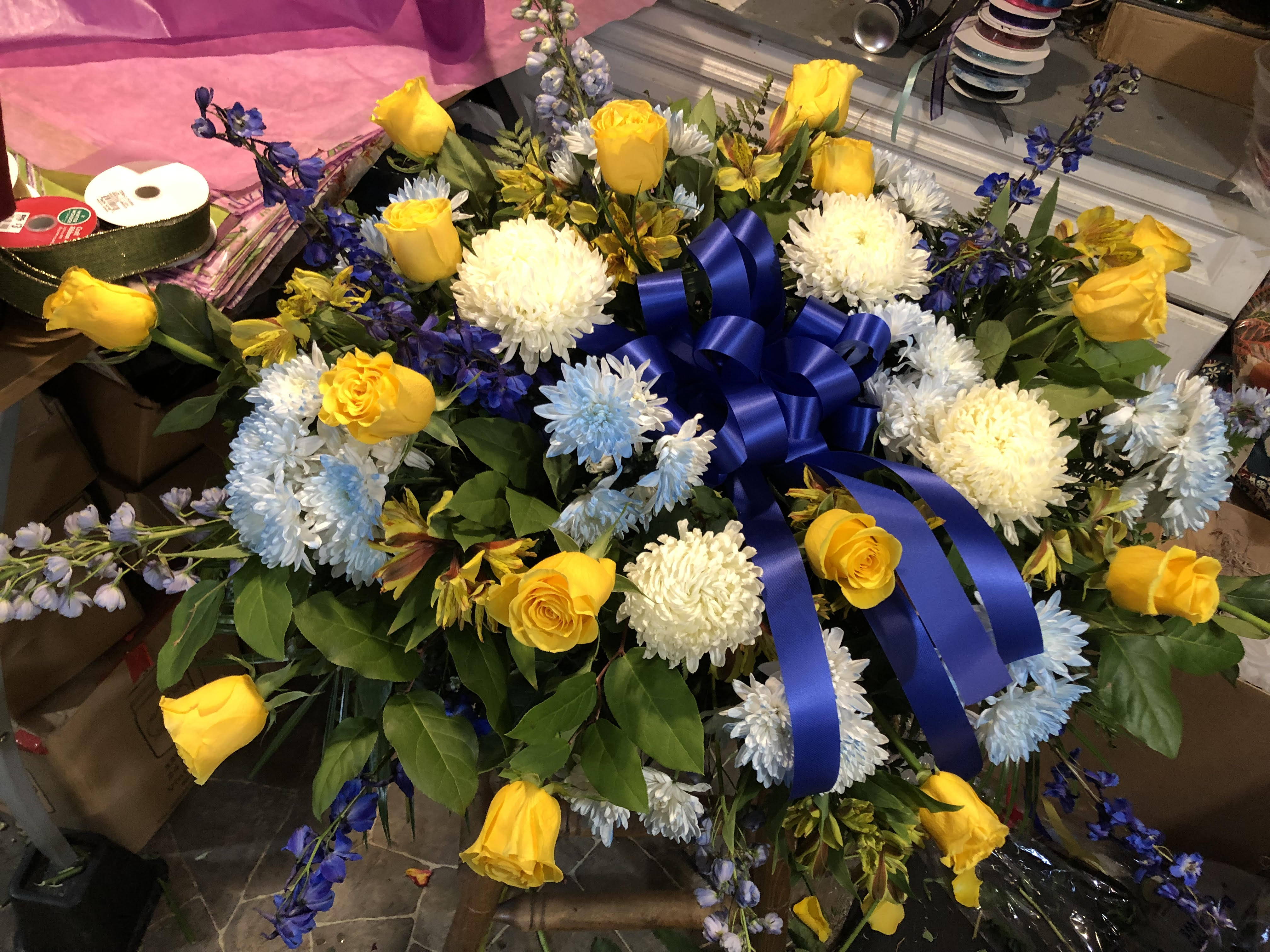 Yellow roses and white chrysanthemums arranged with a blue ribbon bow