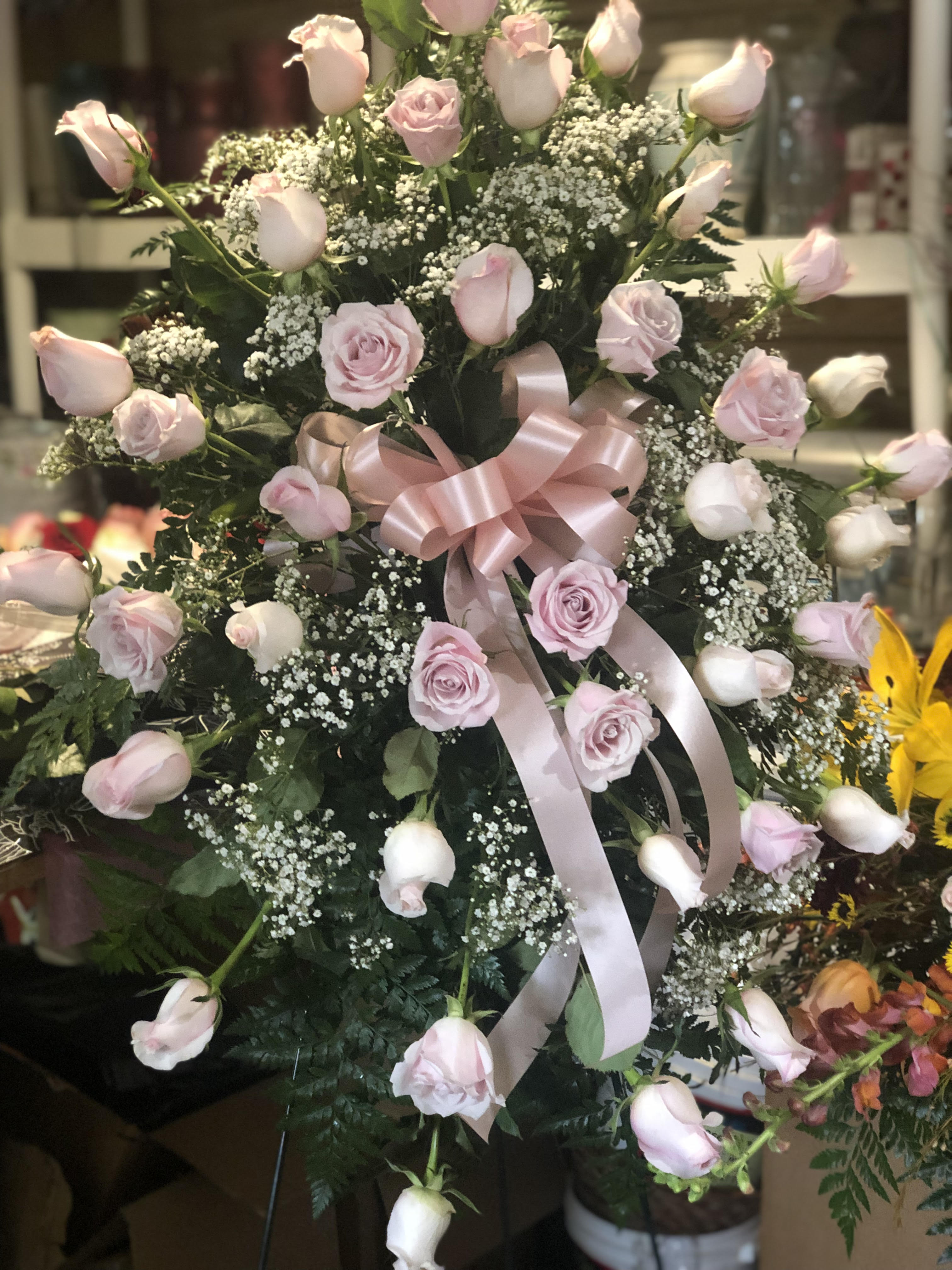 Pink roses and rosebuds arranged with baby's breath and a pink ribbon bow